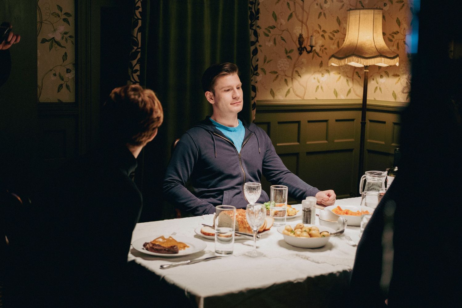 Behind-the-scenes photograph of a restaurant scene being filmed with actors and a professional film crew.