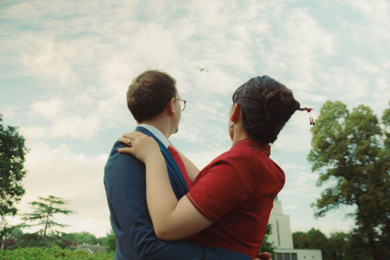 - Romantic couples photograph of a couple embracing in an open field, photographed with a natural cinematic feel.