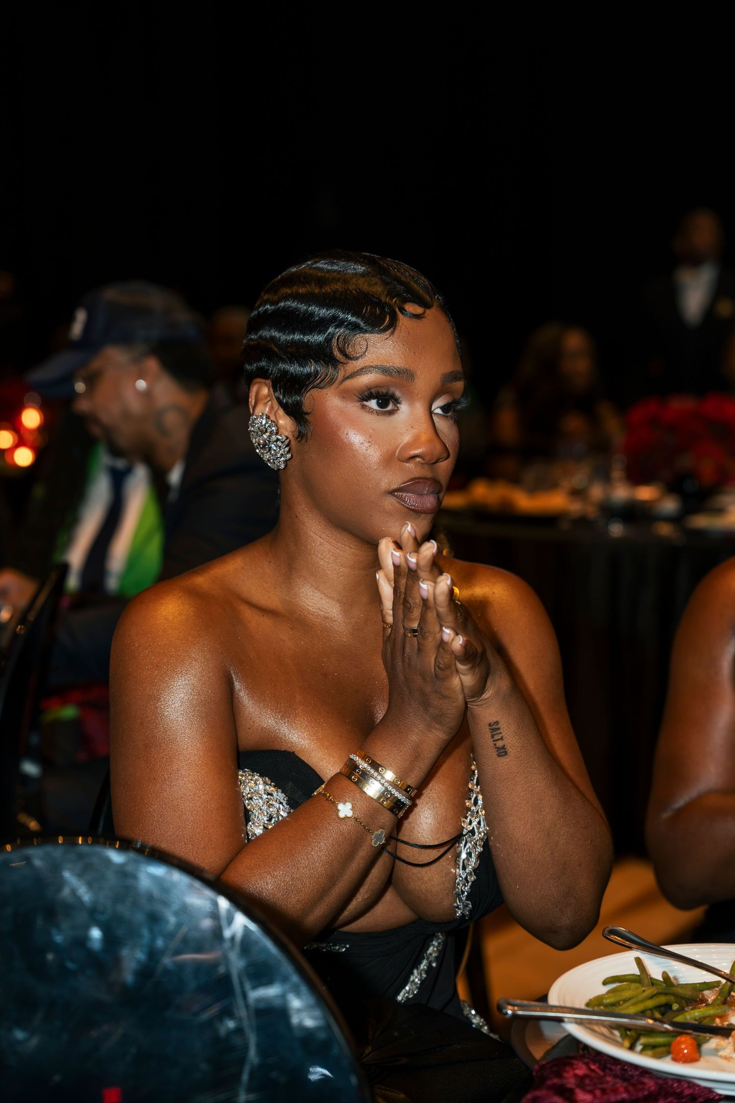 Elegant woman with finger waves hairstyle and rhinestone earrings sitting at a formal gala dinner table.