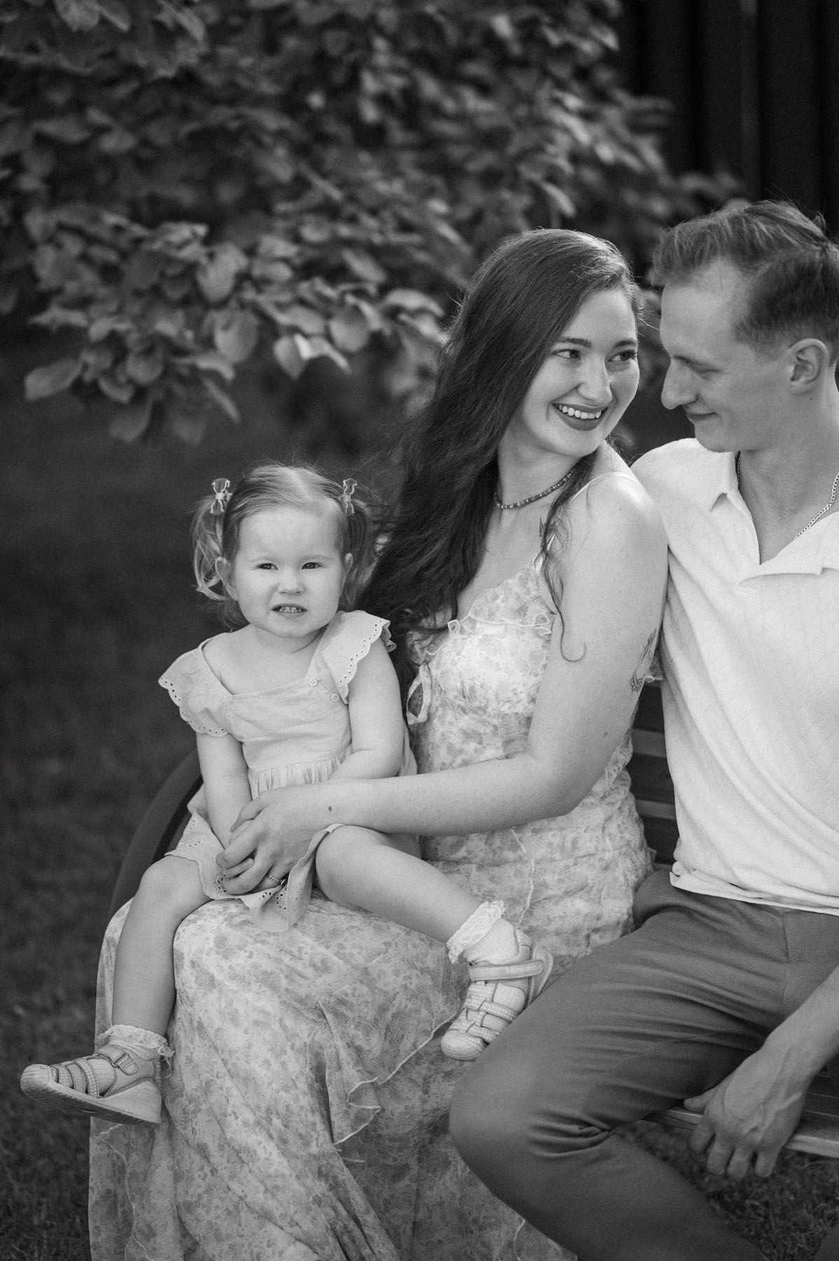 Black and white family portrait of parents laughing with toddler outdoors
