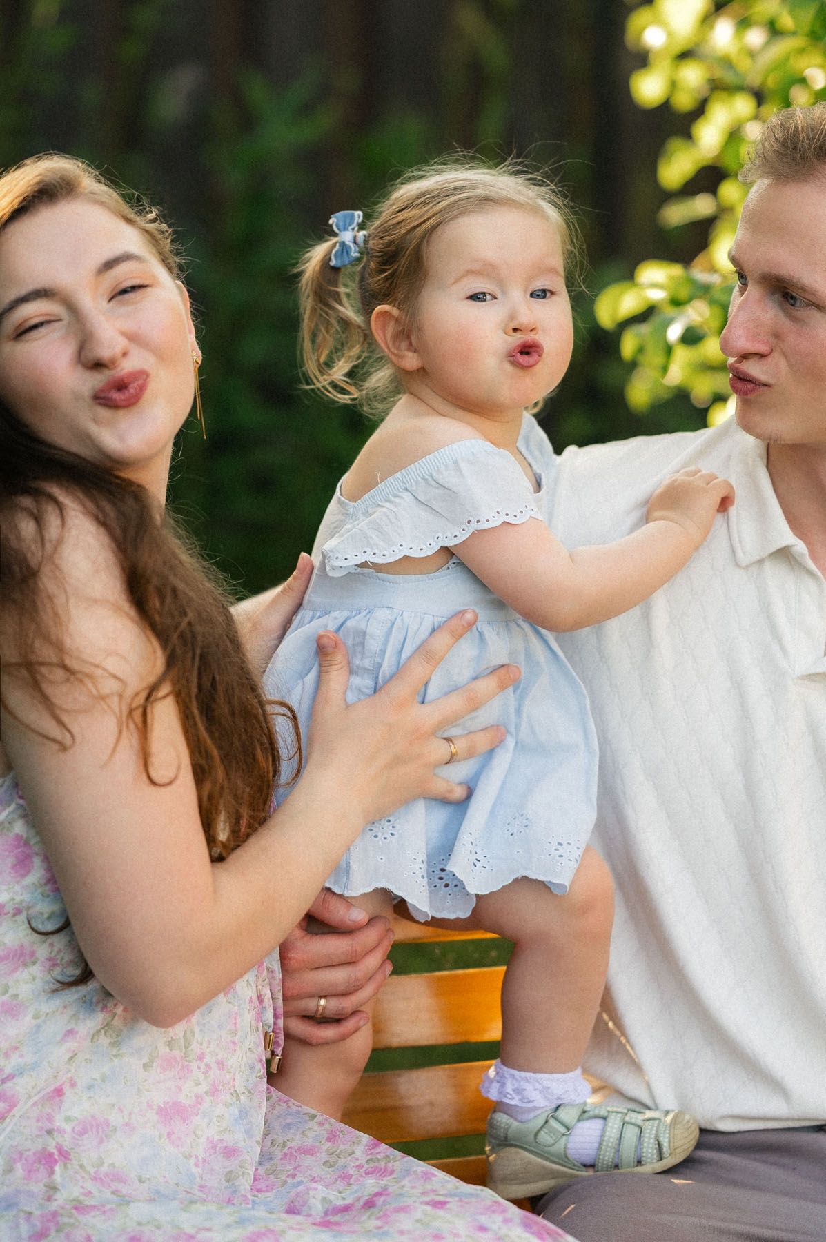 Parents holding toddler daughter up outdoors, joyful family moment