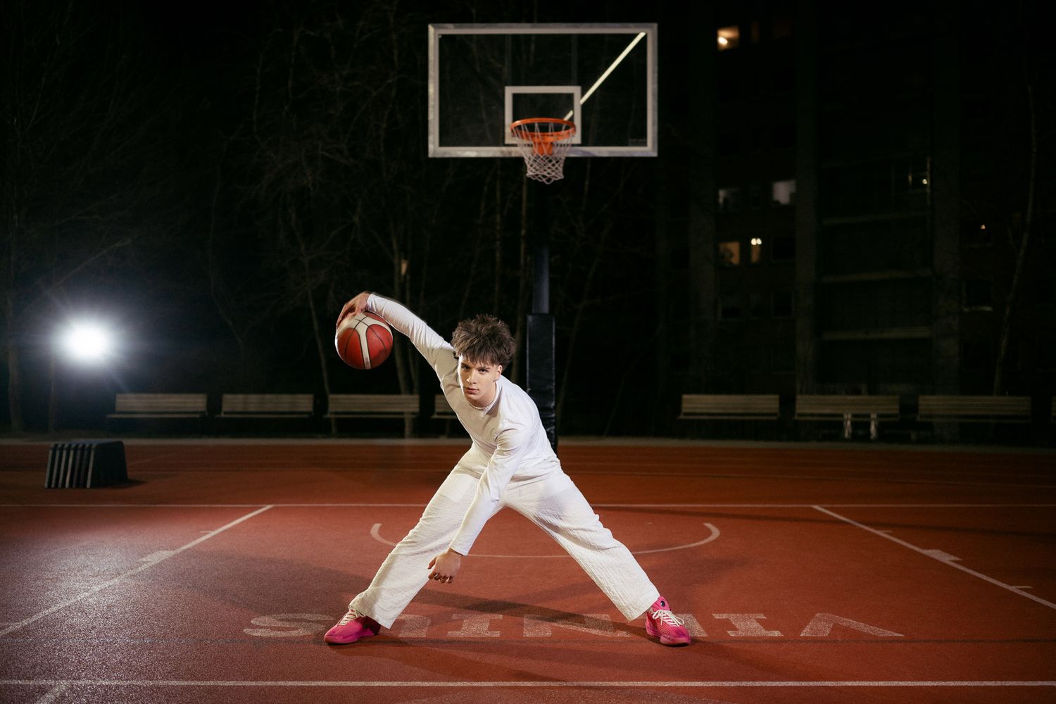Basketball player dribbling on outdoor court under stadium lights, black and white