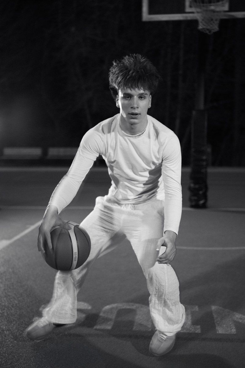 Basketball player in defensive stance dribbling on court at night