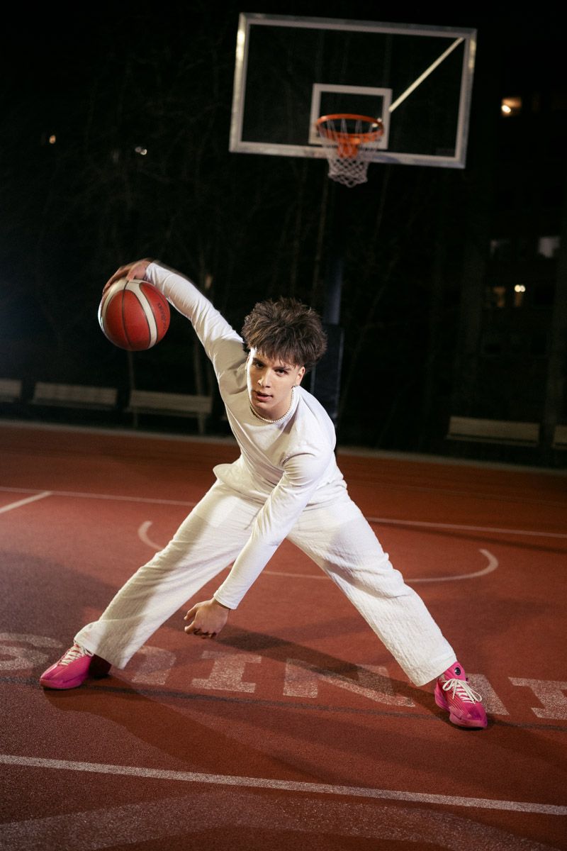 Basketball player crouched dribbling on court, dynamic sports portrait