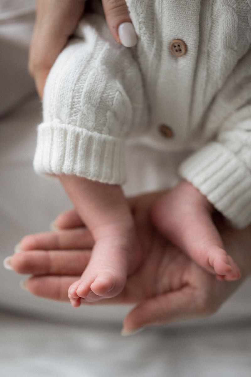 Close-up of mother's hands gently holding newborn baby's tiny feet