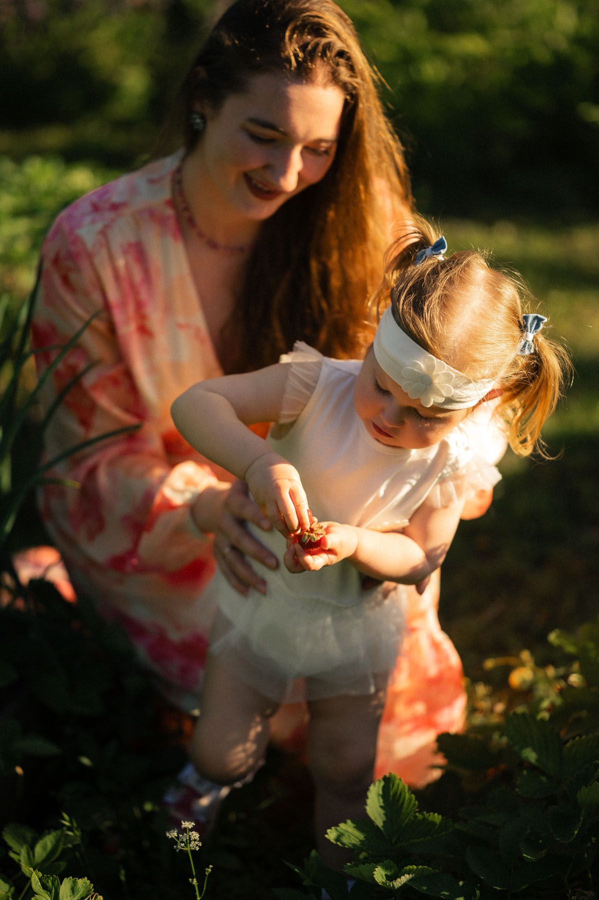 Mother playing with toddler daughter in garden, candid outdoor moment