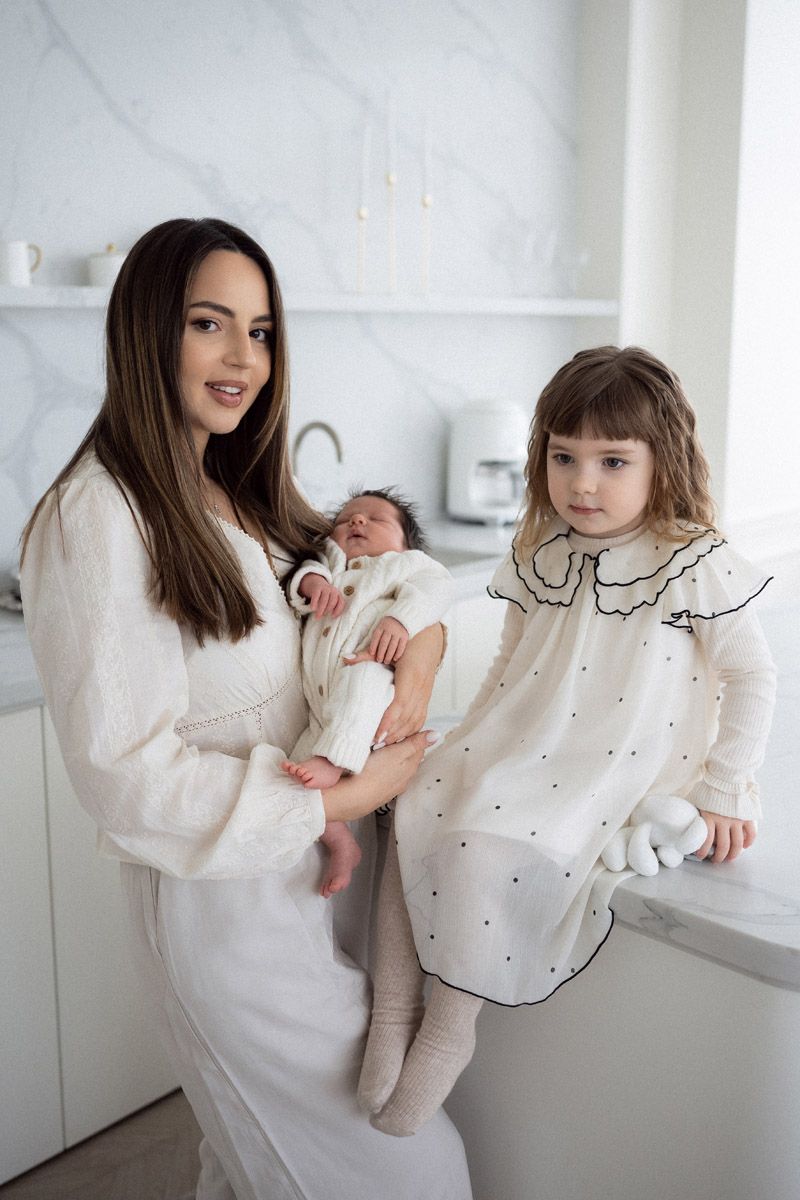 Mother embracing her two daughters and newborn baby, close family portrait