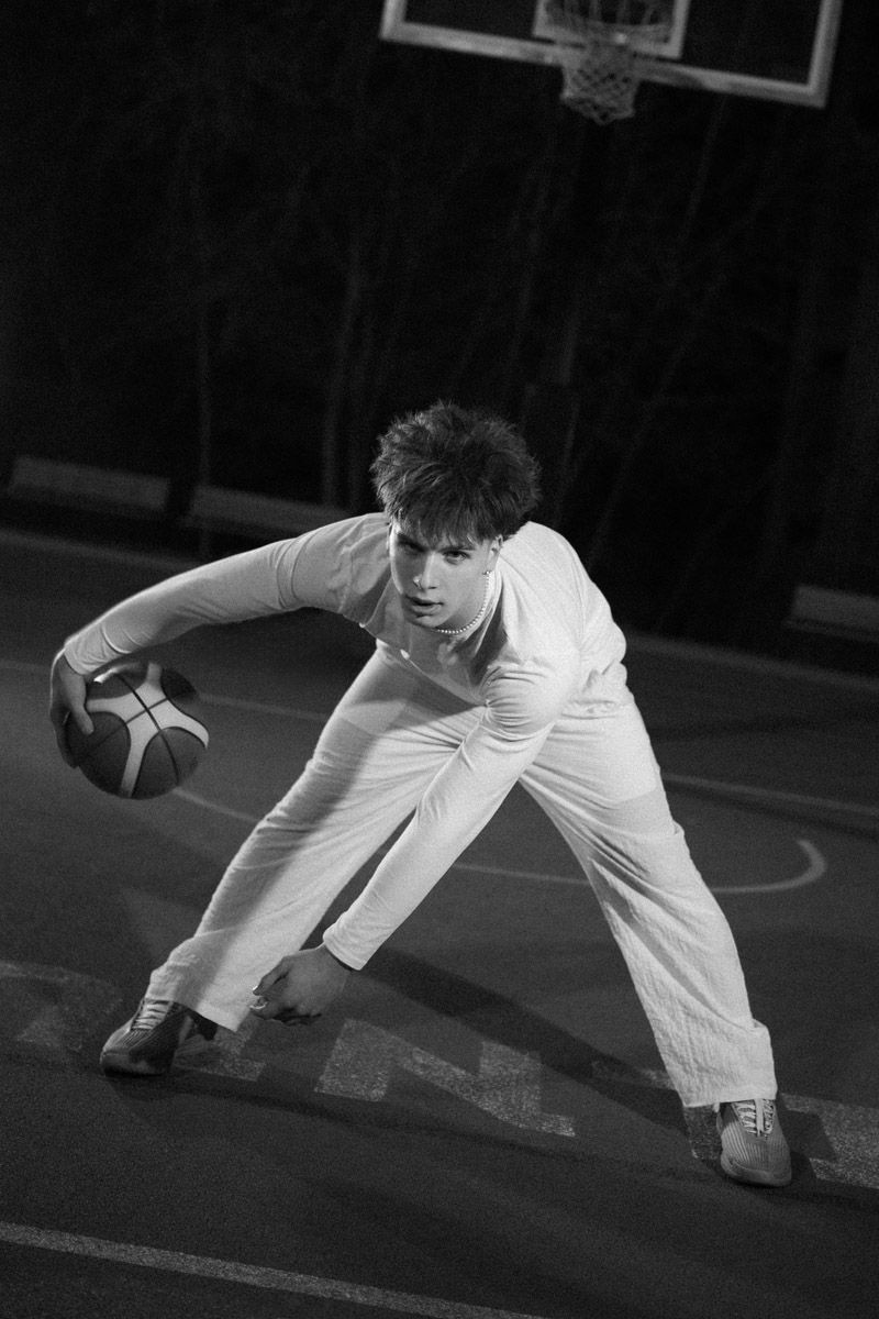 Young basketball player dribbling low on outdoor court, black and white action shot
