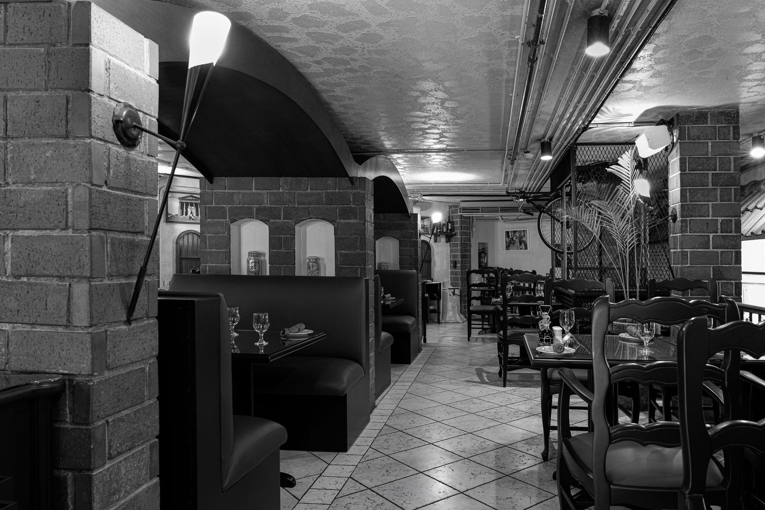 Black and white photo of a cozy restaurant interior with arched brick ceilings, ambient lighting, and elegant table settings.