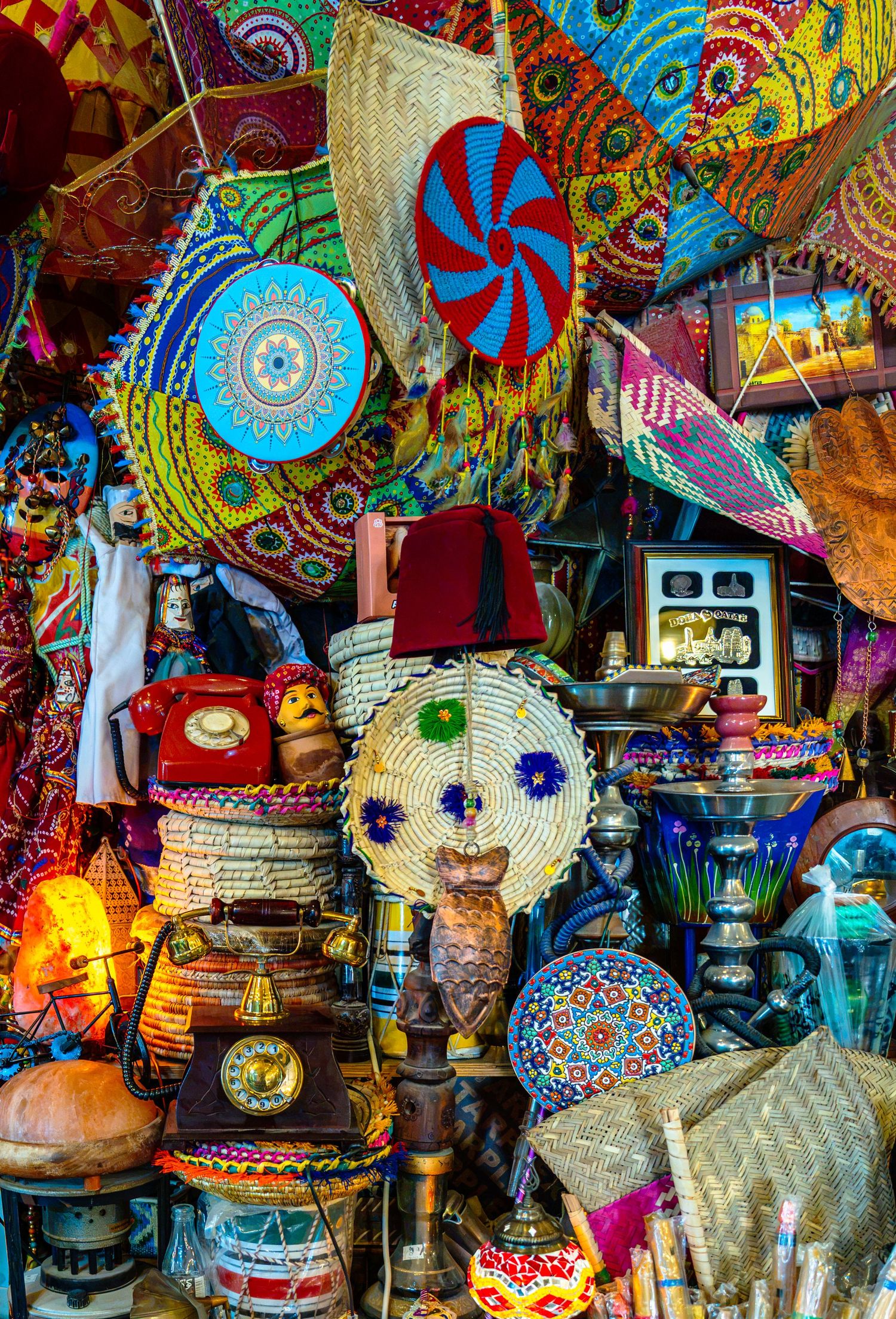 Colorful Moroccan market stall with vibrant woven baskets, vintage telephone, lamps, and decorative crafts.