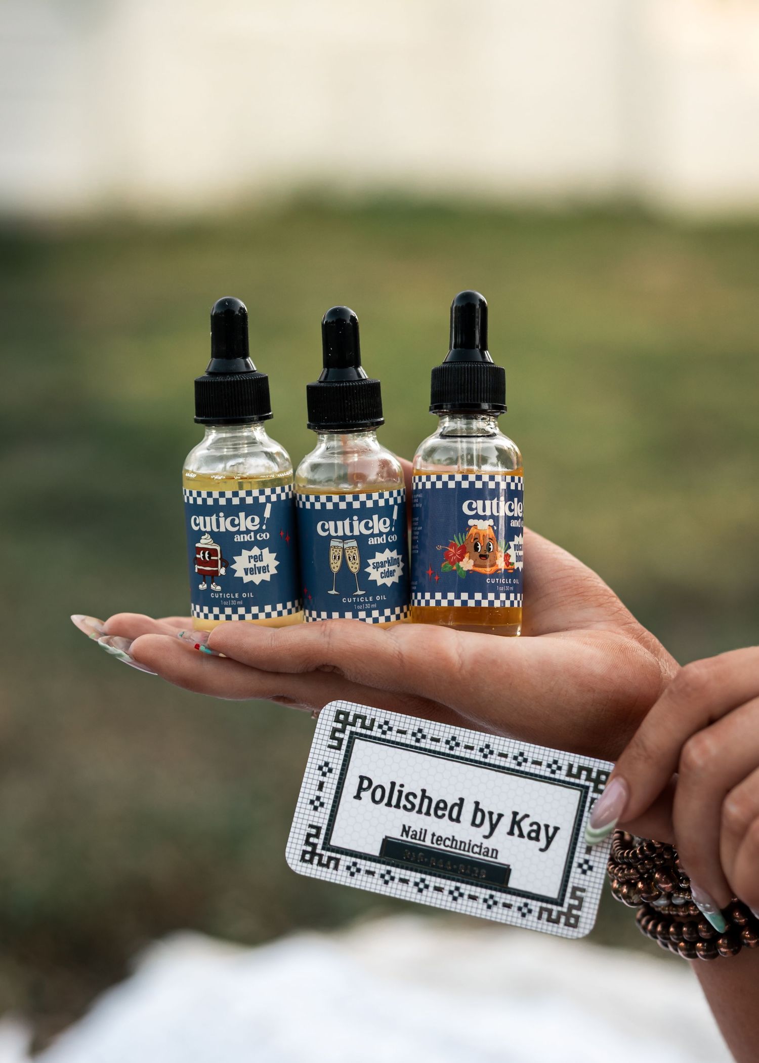 Western Nebraska Brand Session hand holding three Cuticle brand dropper bottles and a Polished by Kay nail technician business card