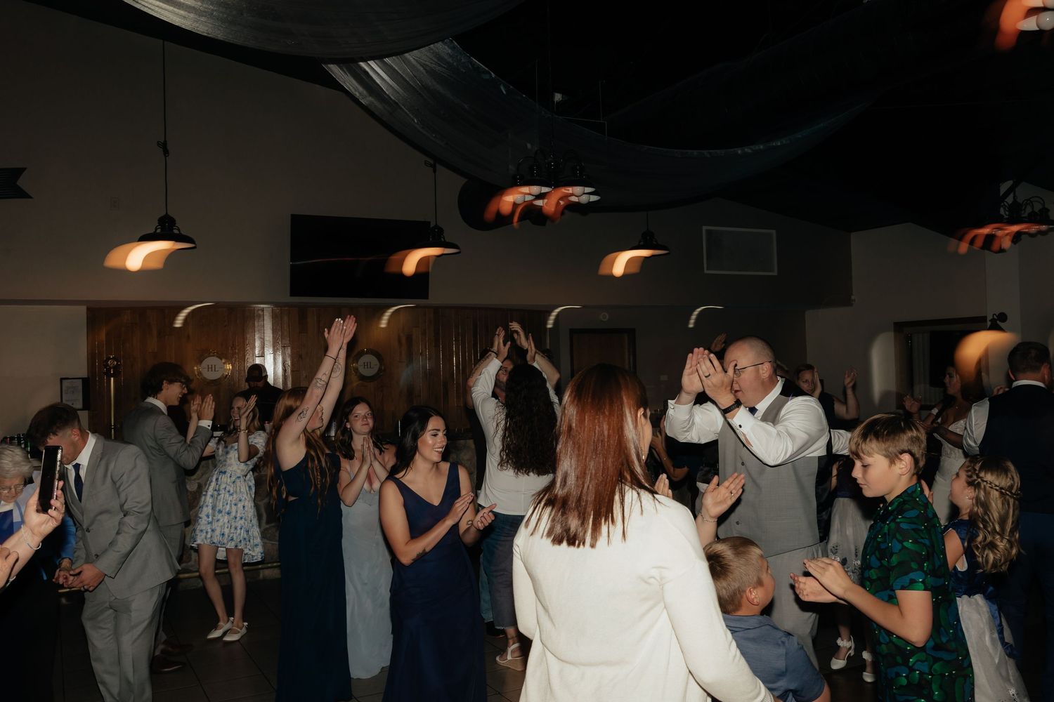 Western Nebraska Wedding Guests dancing and celebrating at a lively wedding reception in a warmly lit venue.