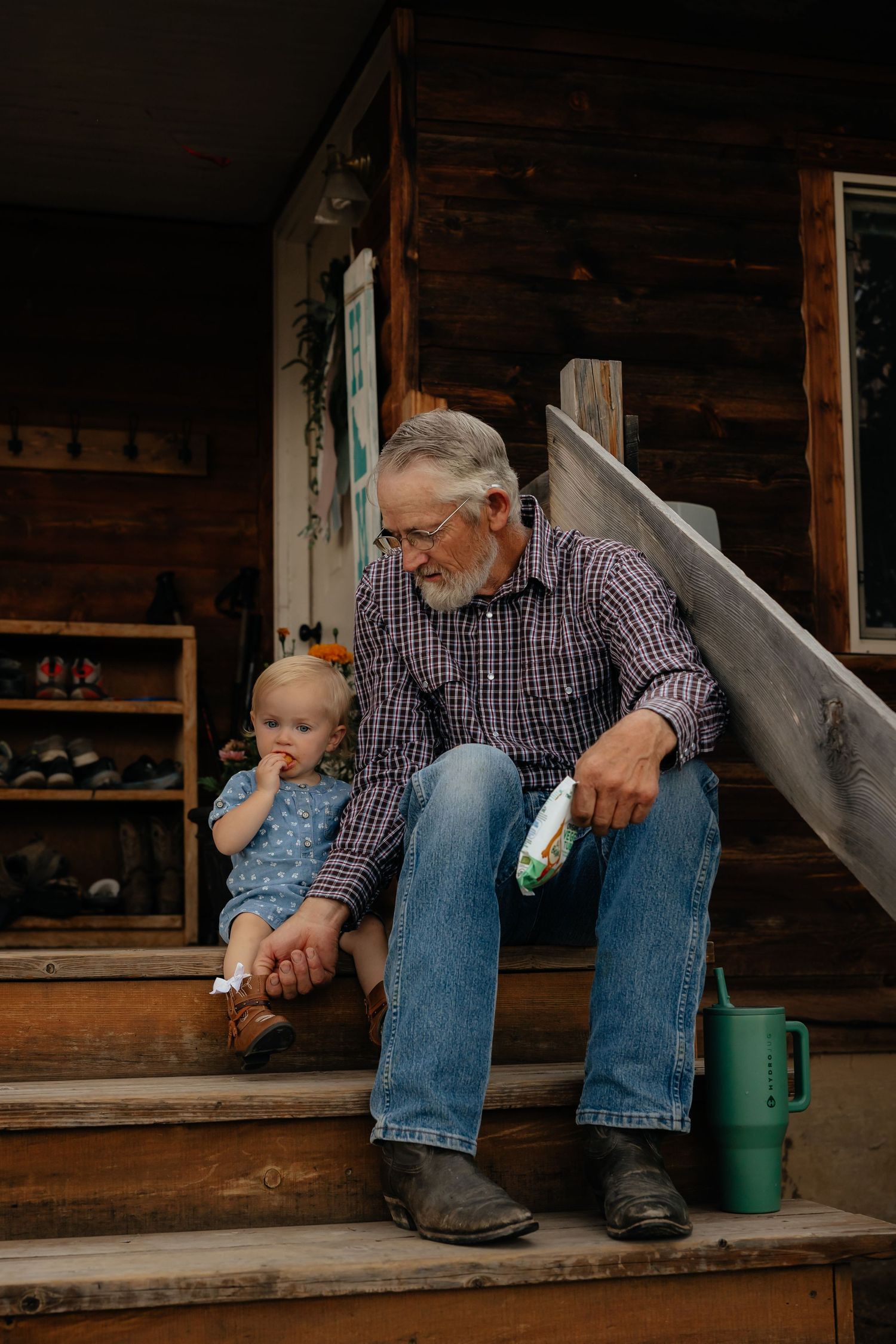 Western Nebraska Family Sessions Elderly man with gray beard sits on wooden porch steps with toddler