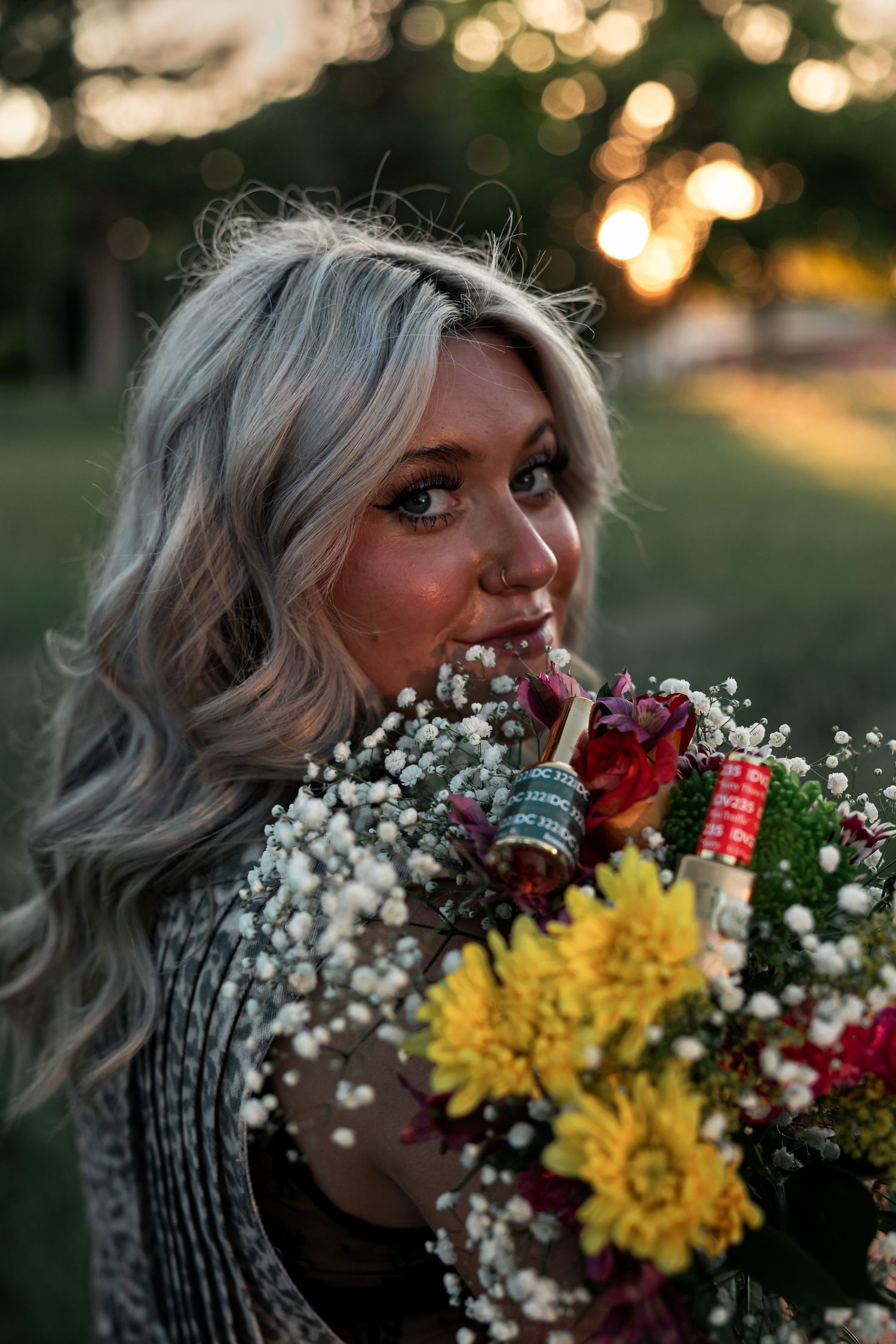 Western Nebraska Brand Session woman holding a colorful bouquet of flowers including yellow mums and baby's breath at golden hour.