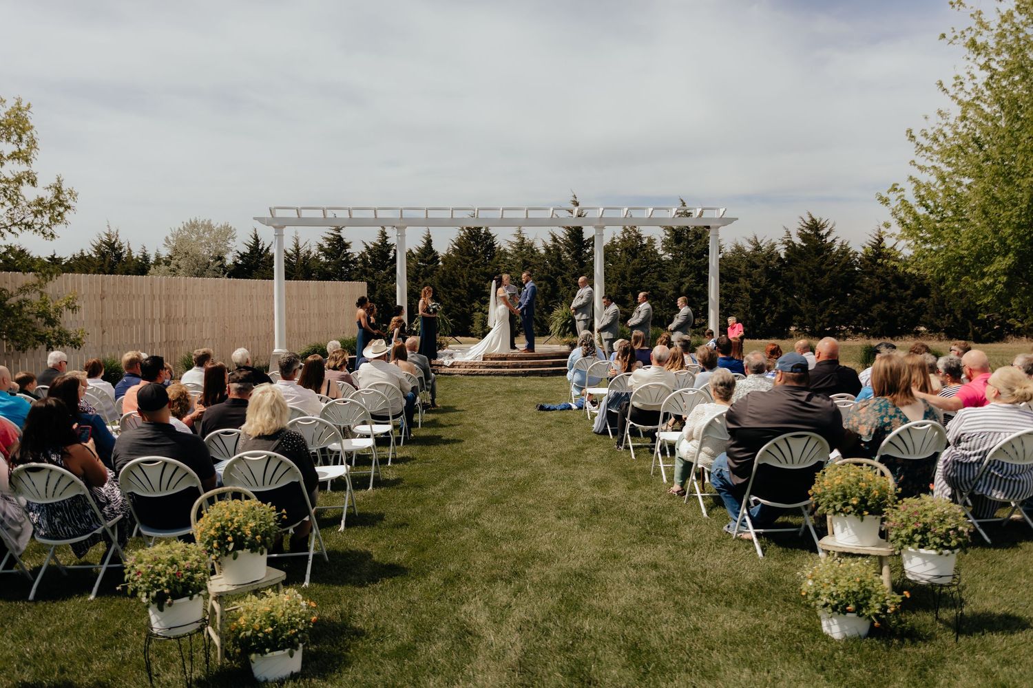 Western Nebraska Wedding outdoor ceremony, rows of guests seated in chairs, and potted plant aisle decor.