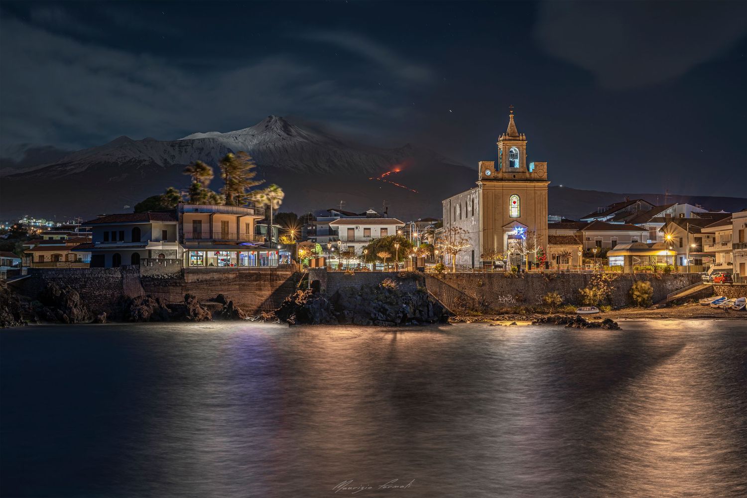 Vista notturna dal porto di Stazzo con l’Etna in eruzione sullo sfondo