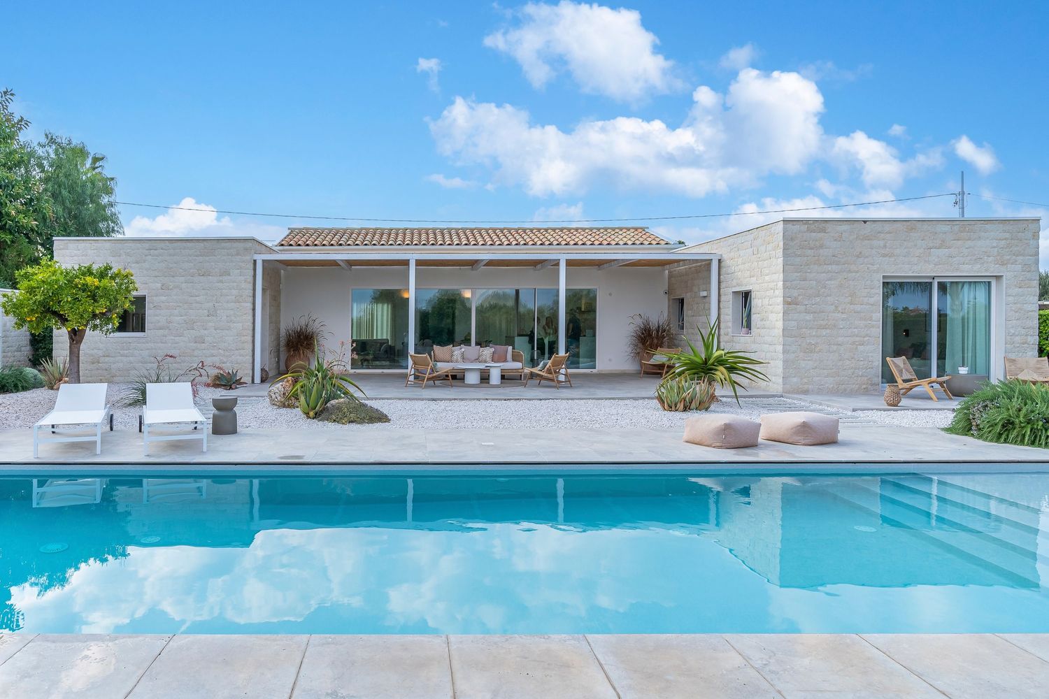Elegante villa di lusso con piscina, valorizzata dalla luce naturale e dalla raffinata architettura degli spazi esterni.