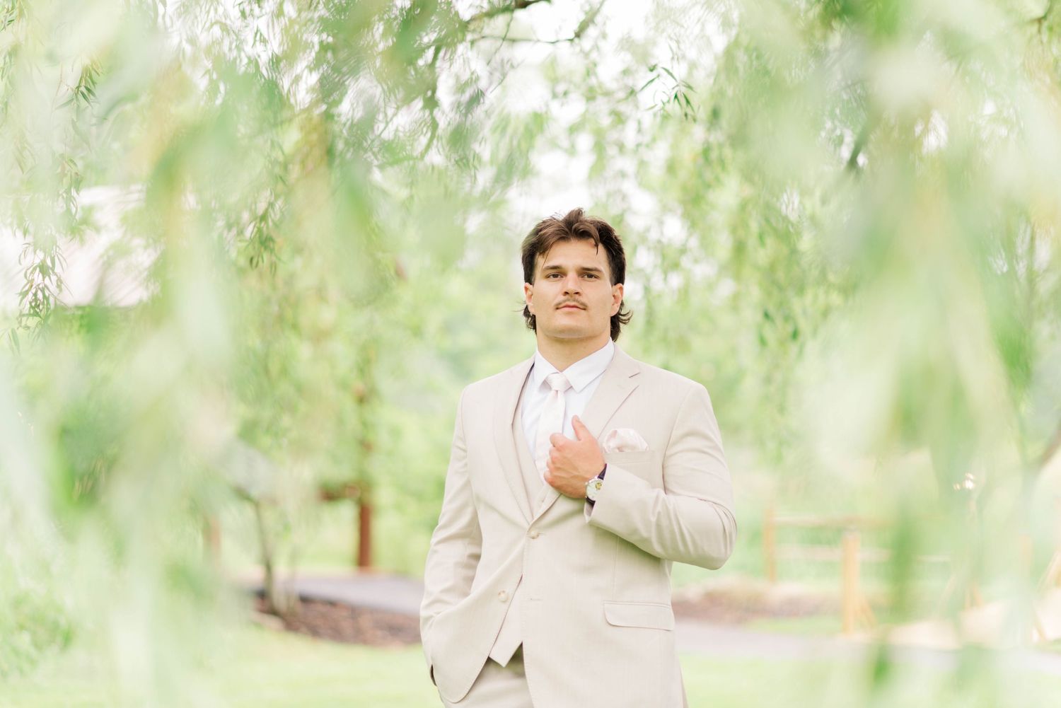 Groom under a willow tree at Whispering Hollow Estates in Pleasantville, Pennsylvania