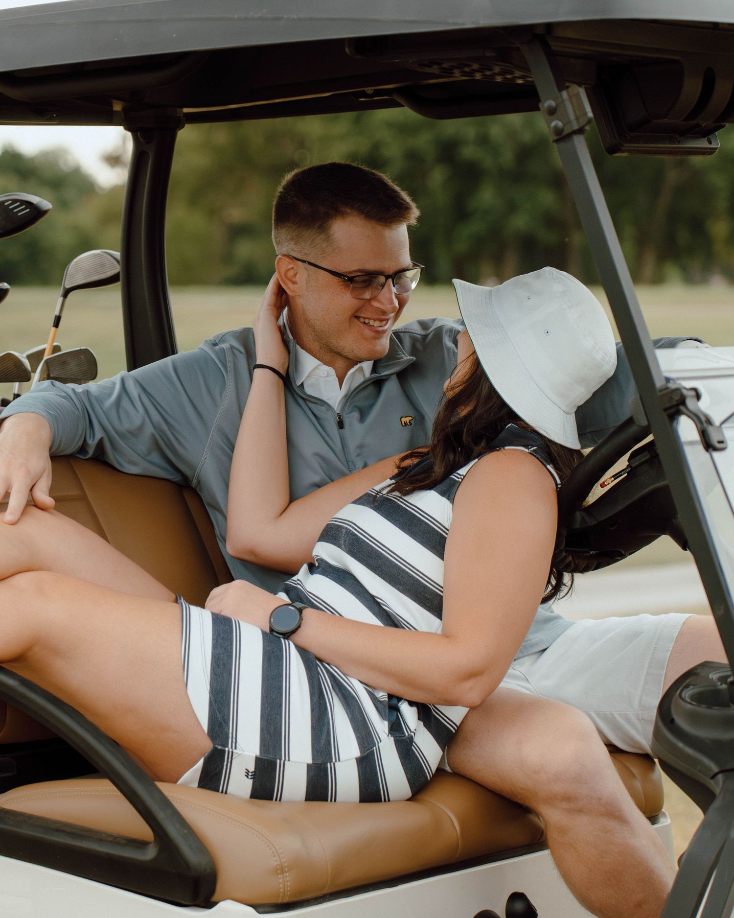 Couple sharing romantic moment sitting together in golf cart on sunny day.