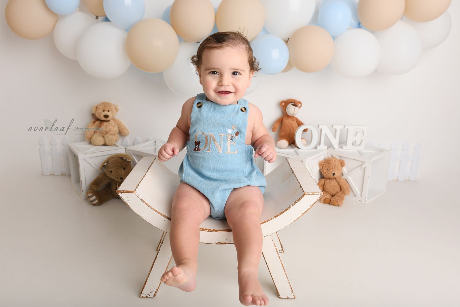 Baby seated with balloons and teddy bears for a first birthday portrait