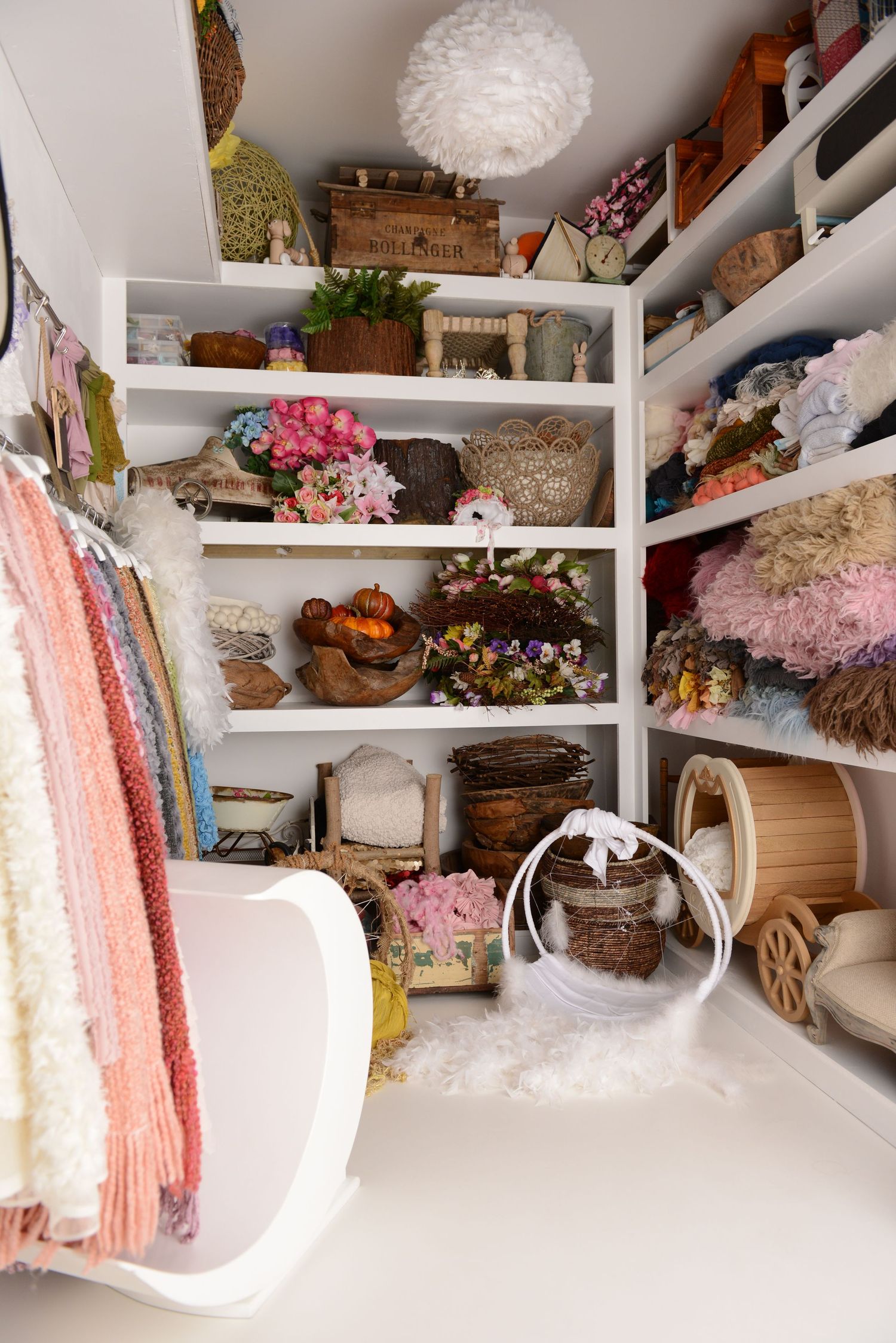 Studio shelves filled with newborn wraps, props and portrait accessories