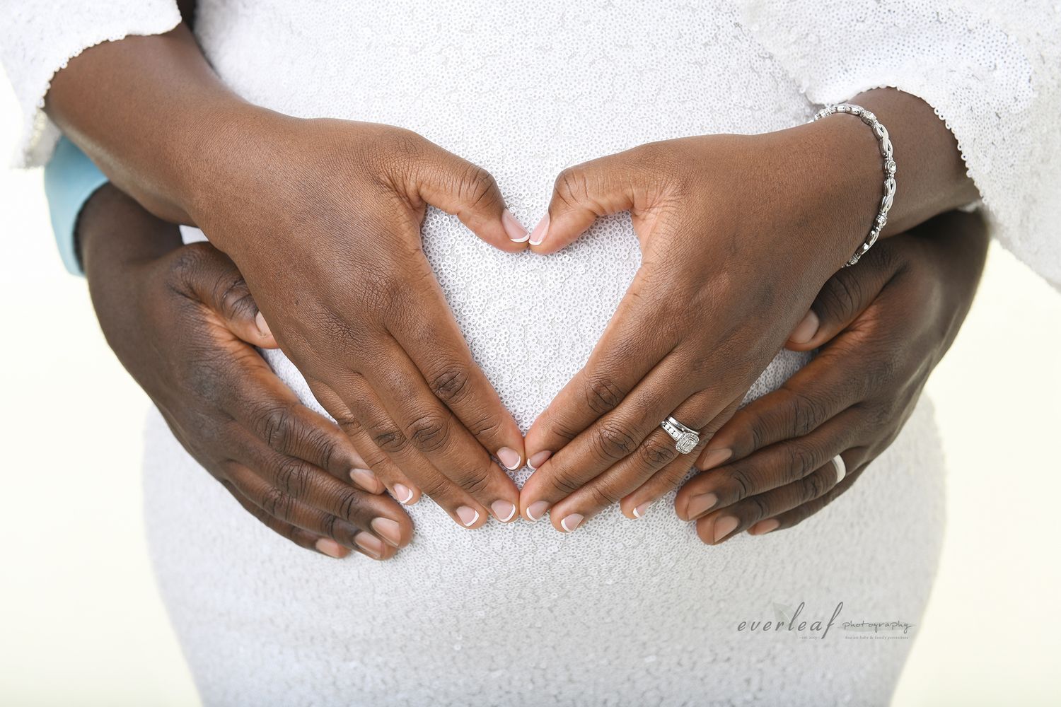 Pregnant woman forming a heart with her hands over her baby bump