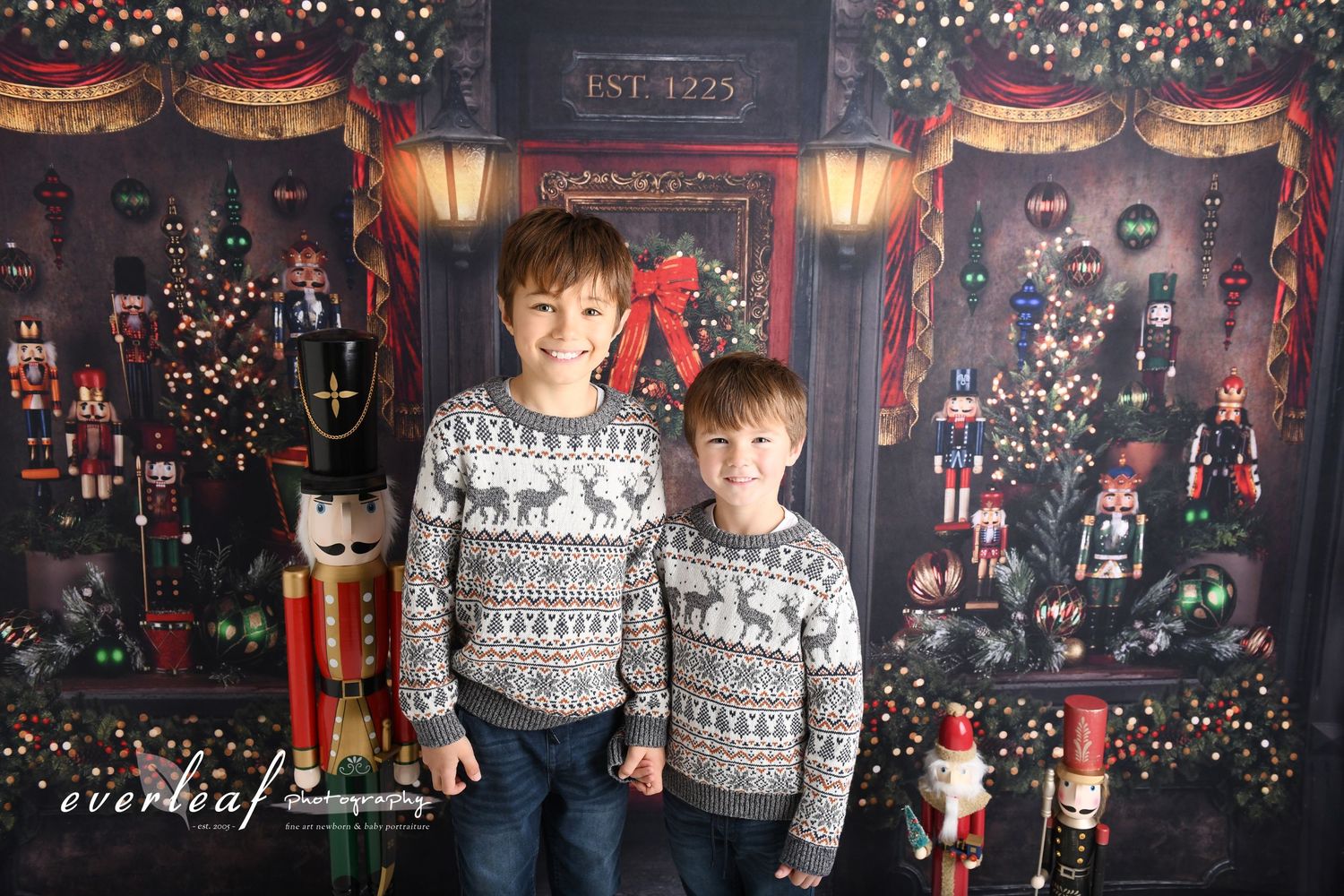 Two brothers in matching Christmas jumpers beside nutcracker decorations in the Everleaf Photography studio.