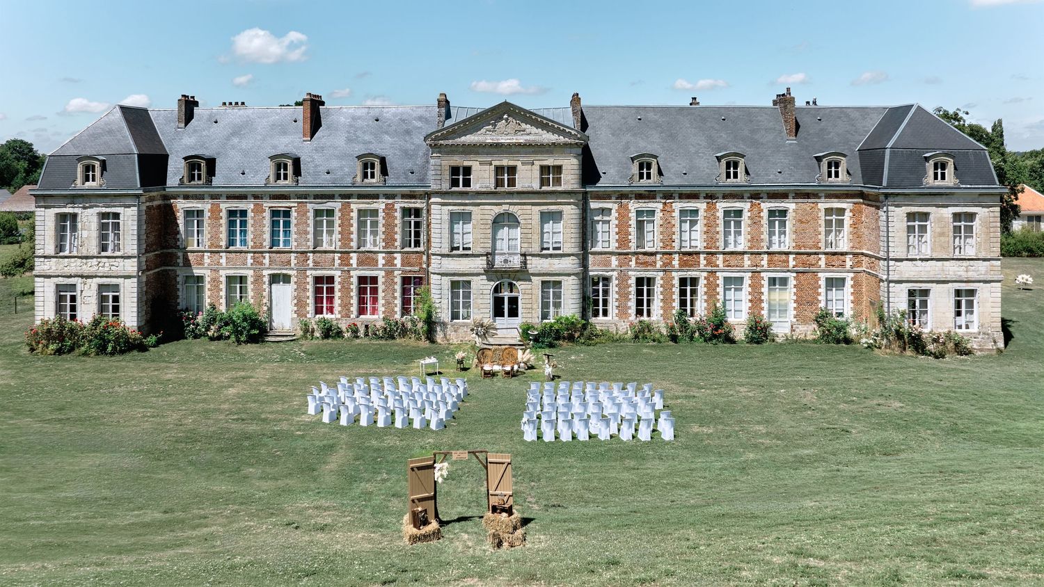 Lieu de réception avec cérémonie de mariage installée en extérieur devant un château