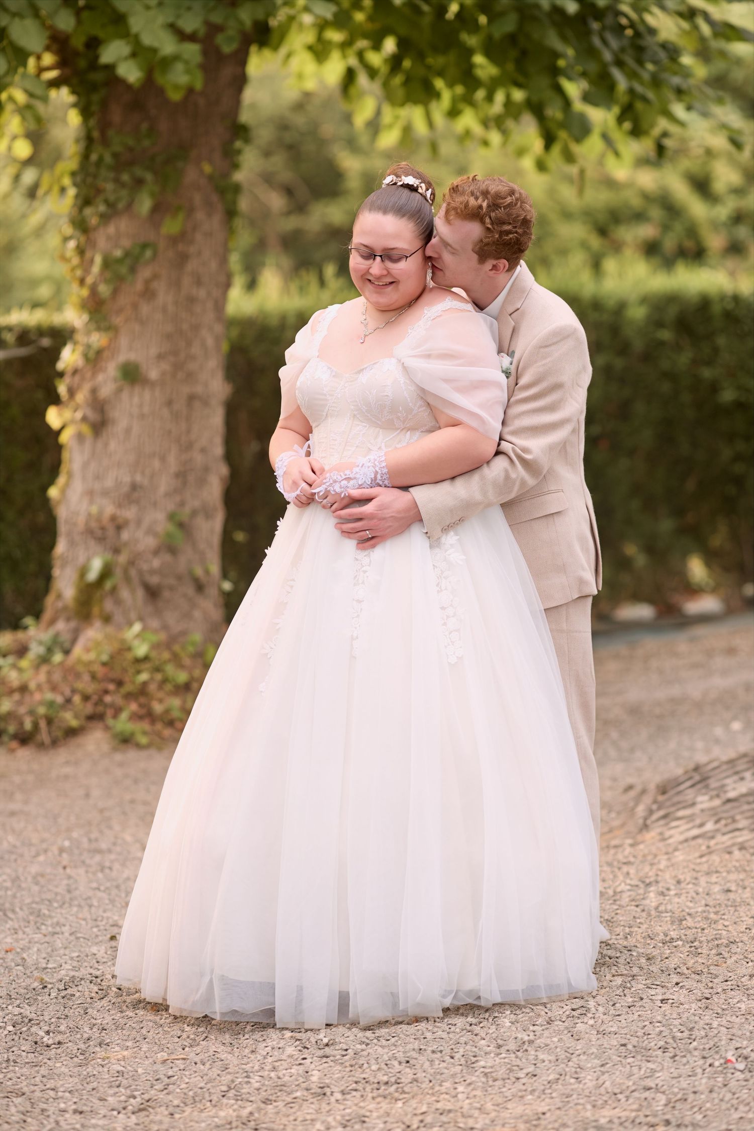 Mariés enlacés en extérieur, le marié derrière la mariée
