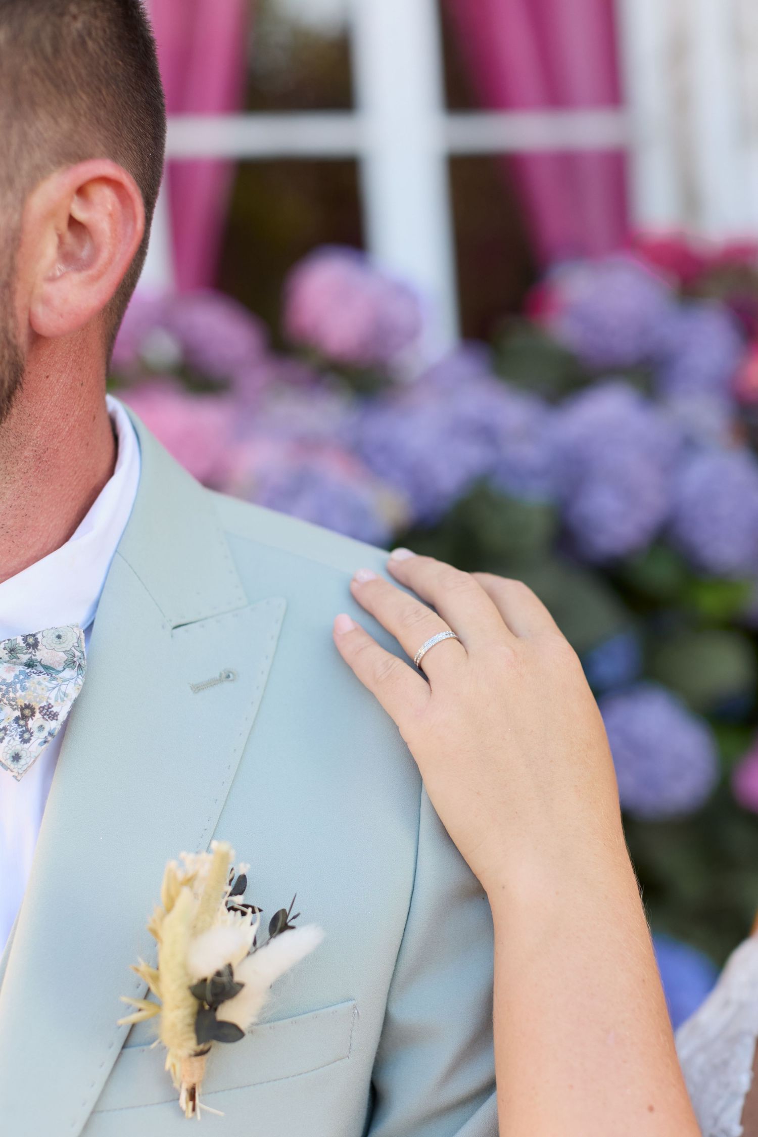 Détail de la main de la mariée posée sur l’épaule du marié