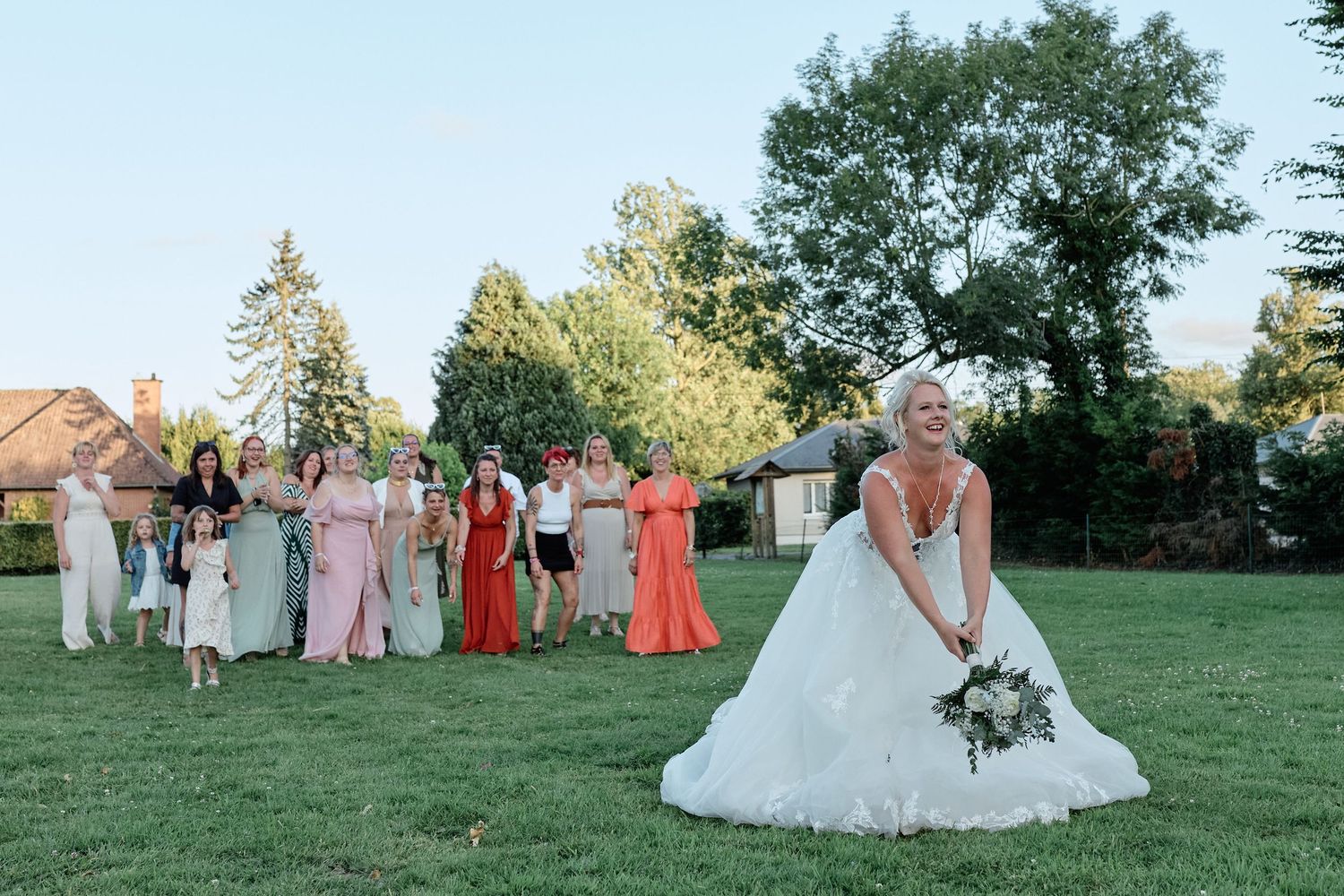 Mariée tenant son bouquet devant ses invités dans un jardin