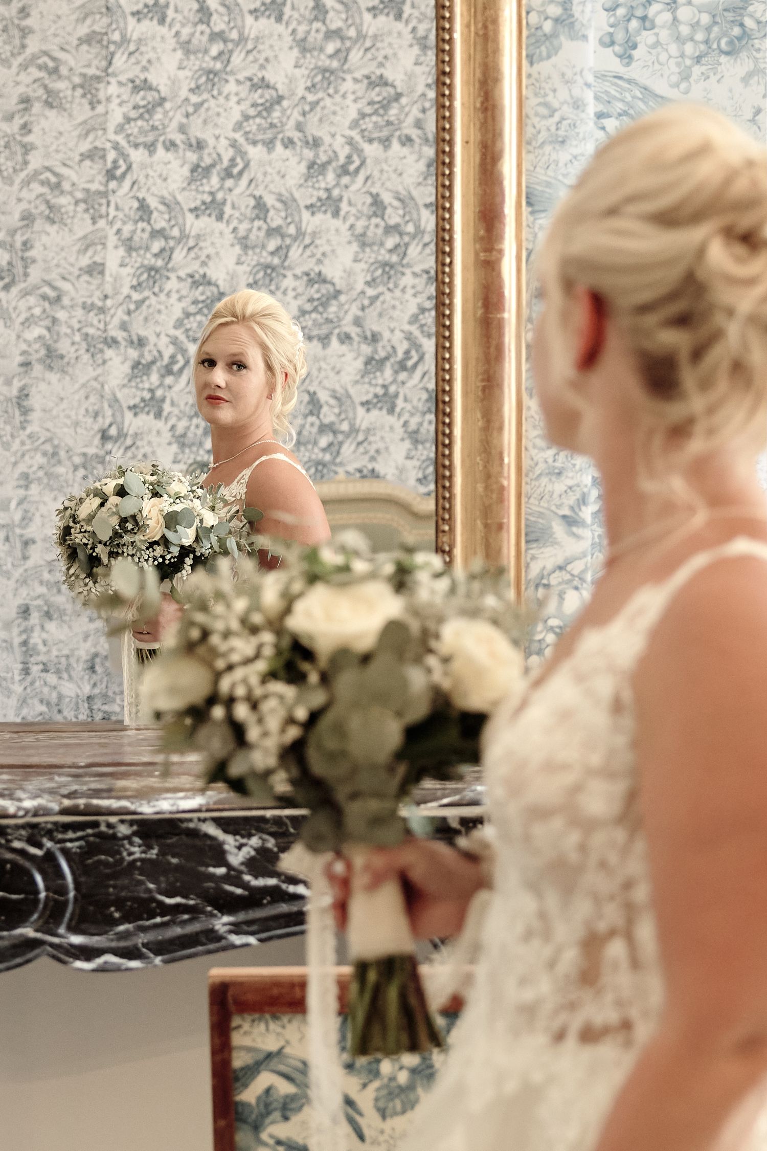 Mariée devant un miroir avec son bouquet pendant les préparatifs