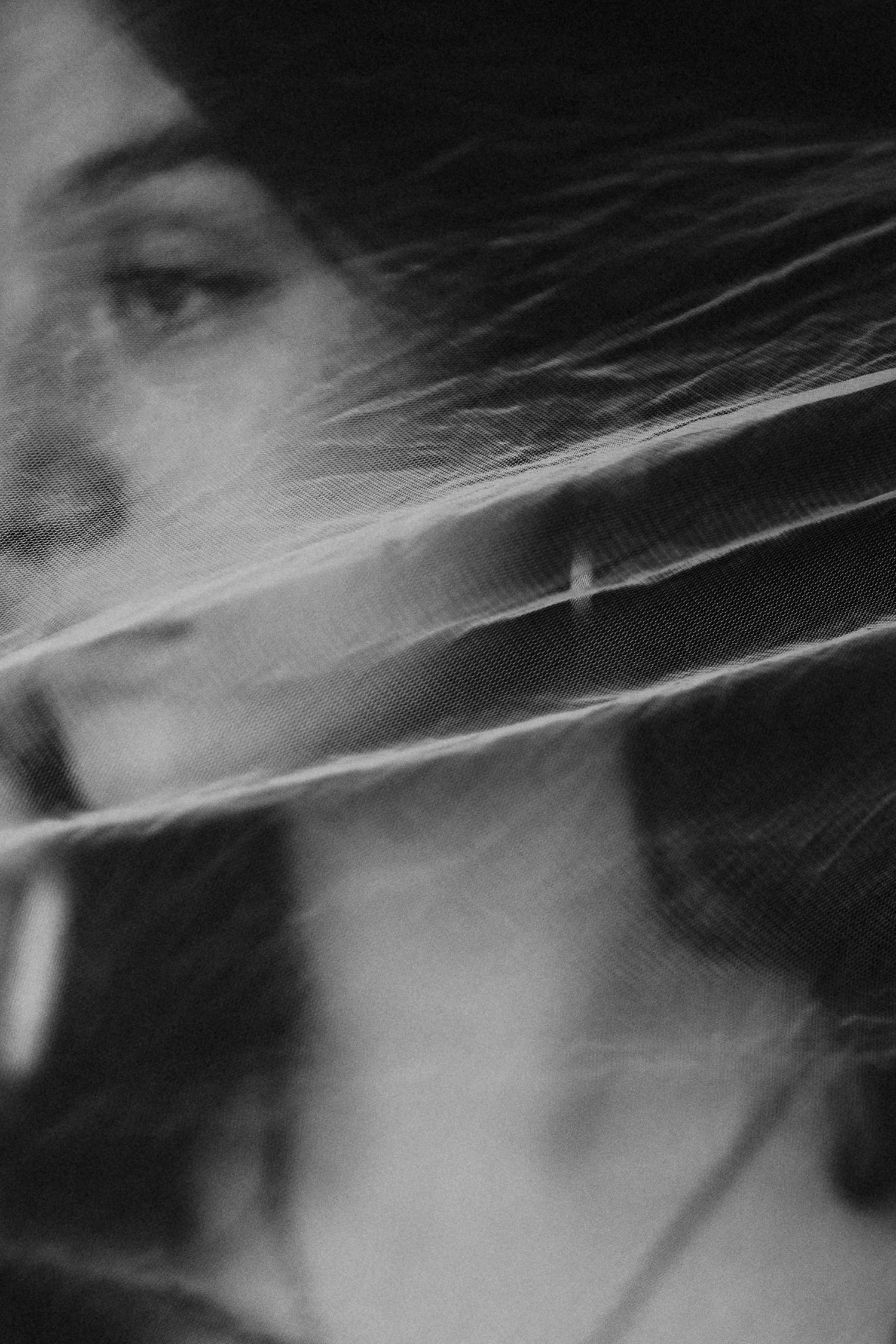 Black and white portrait of a woman with hair blowing across her face, creating a dramatic, artistic effect.