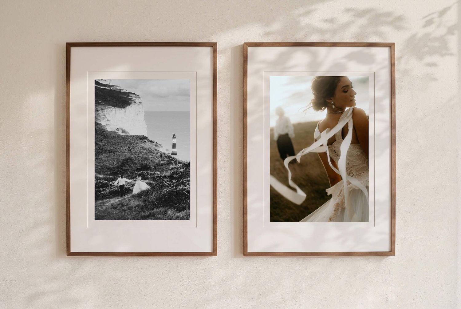 Two framed fine art prints on a wall, one coastal black and white, one elegant bridal portrait.