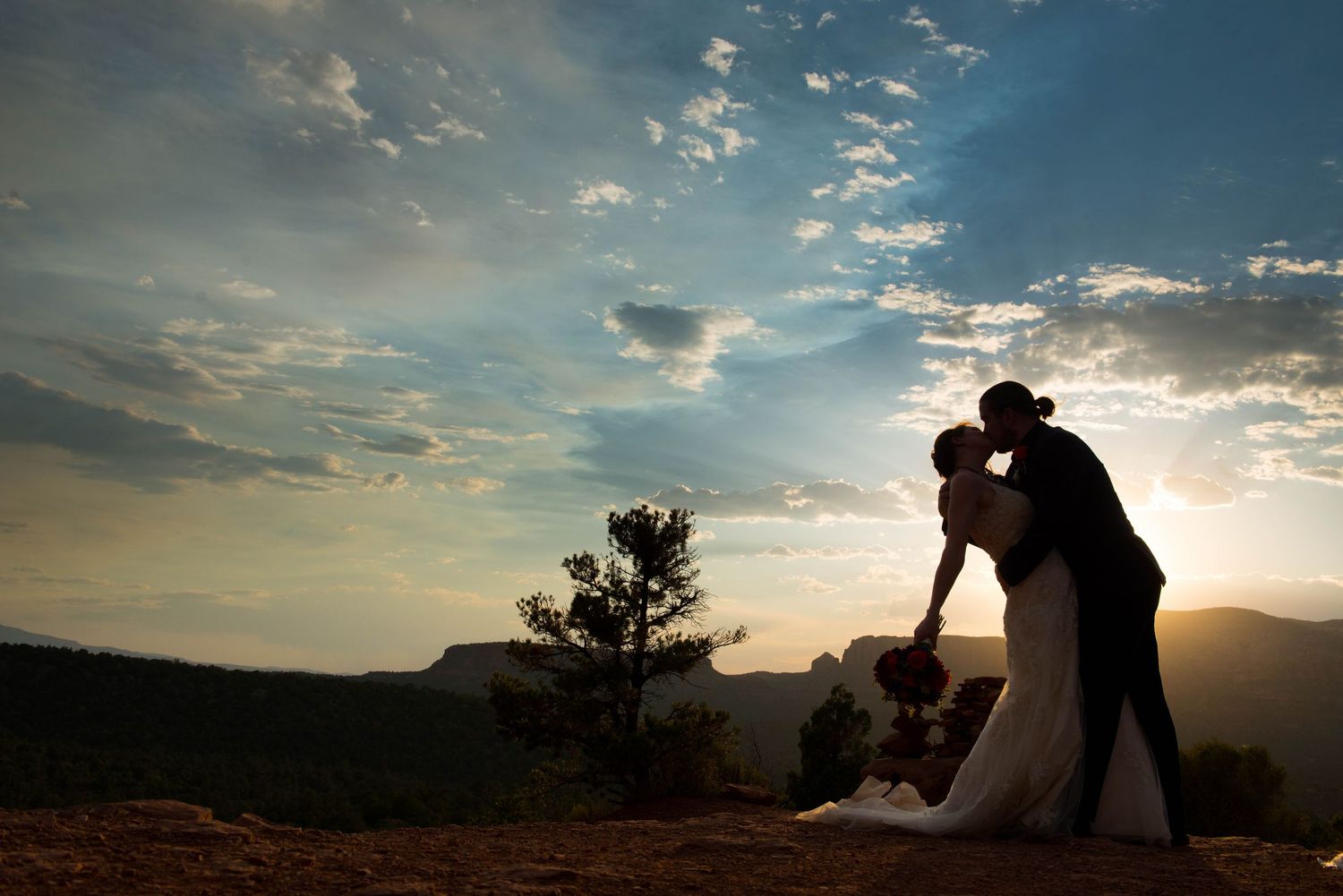 Silhouette of a bride and groom kissing at sunset among the red rocks of Sedona, Arizona.