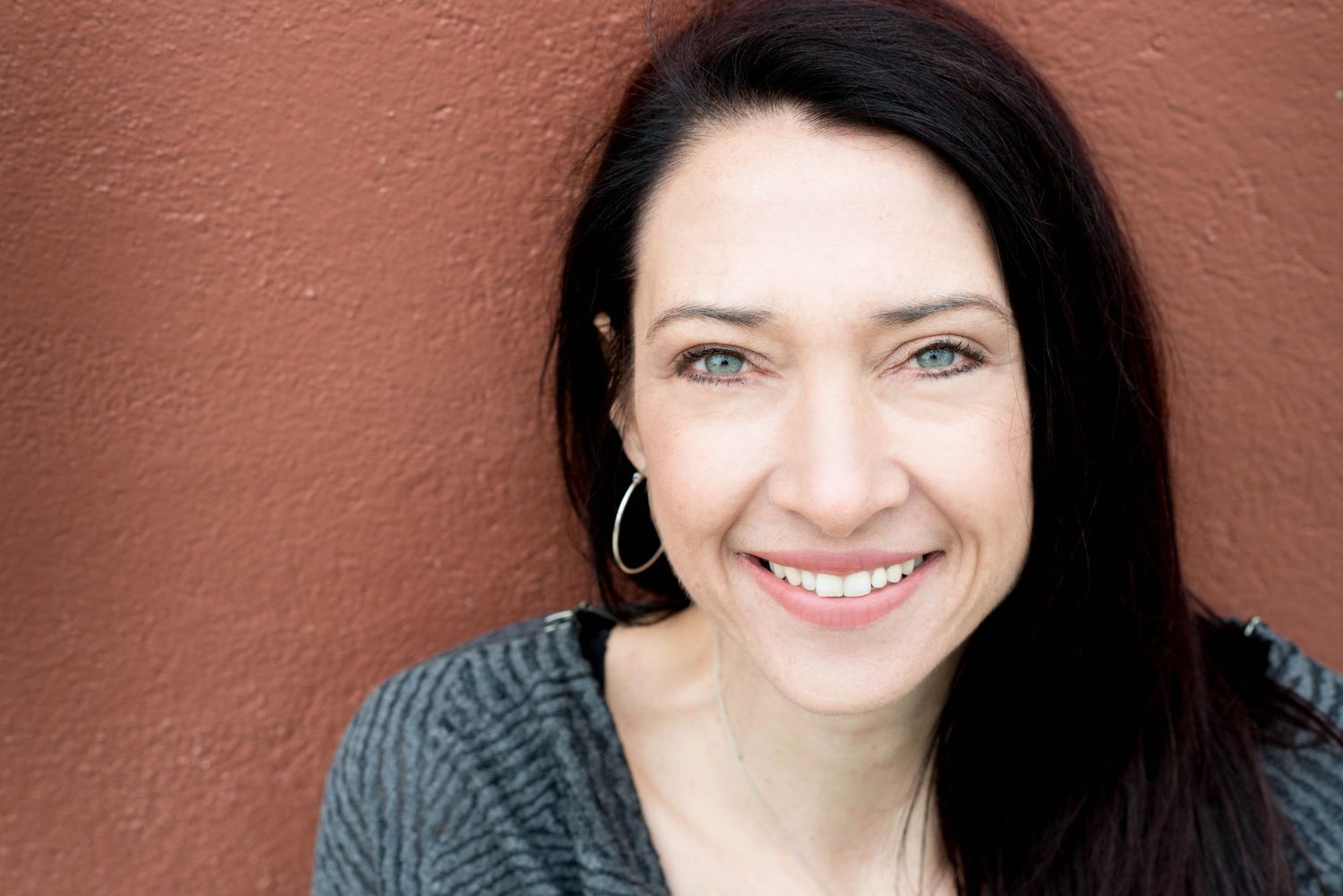 Professional headshot of a smiling woman against a terracotta wall in Chilliwack, British Columbia.