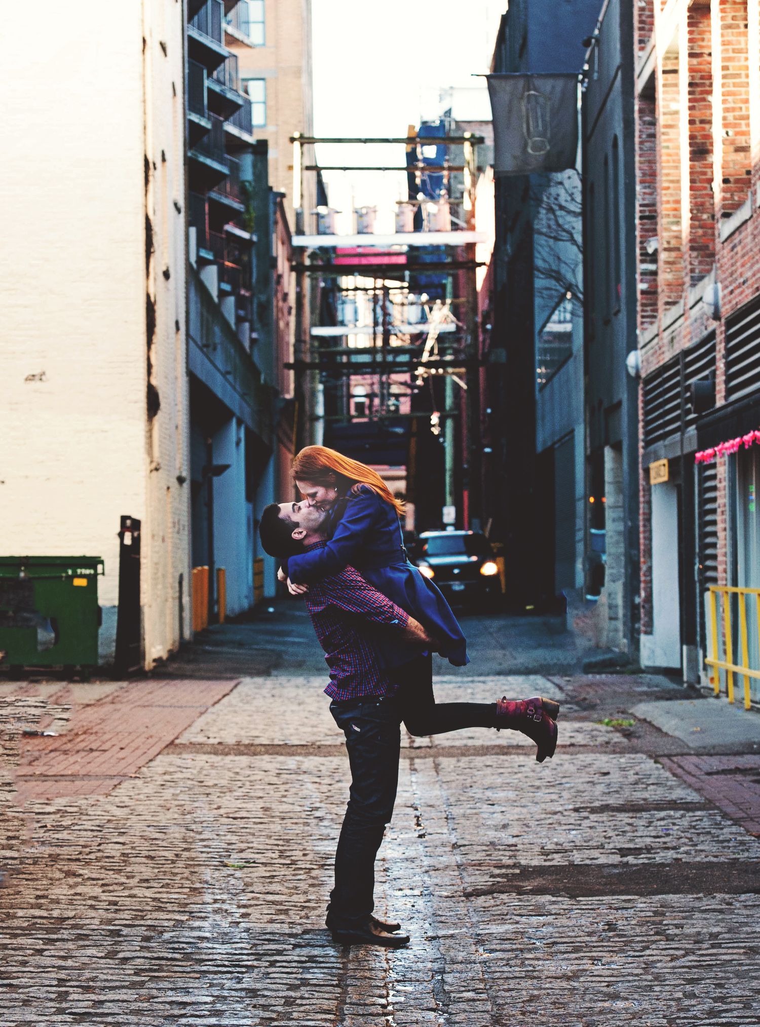 Couple sharing a joyful embrace in a rain-slicked alley during an engagement session in Vancouver, British Columbia.