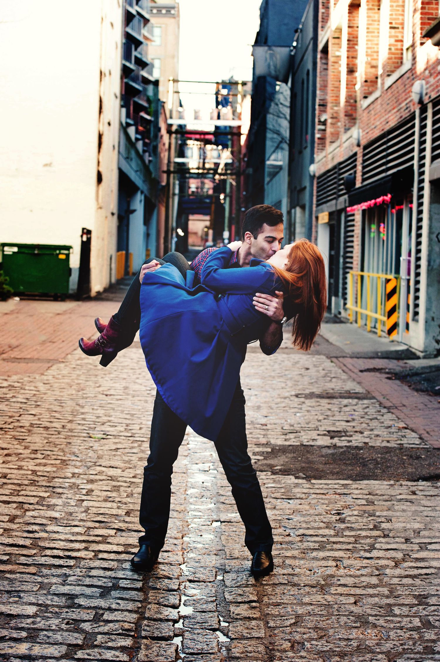 Couple sharing a dramatic dip kiss during an engagement session in downtown Vancouver, British Columbia.