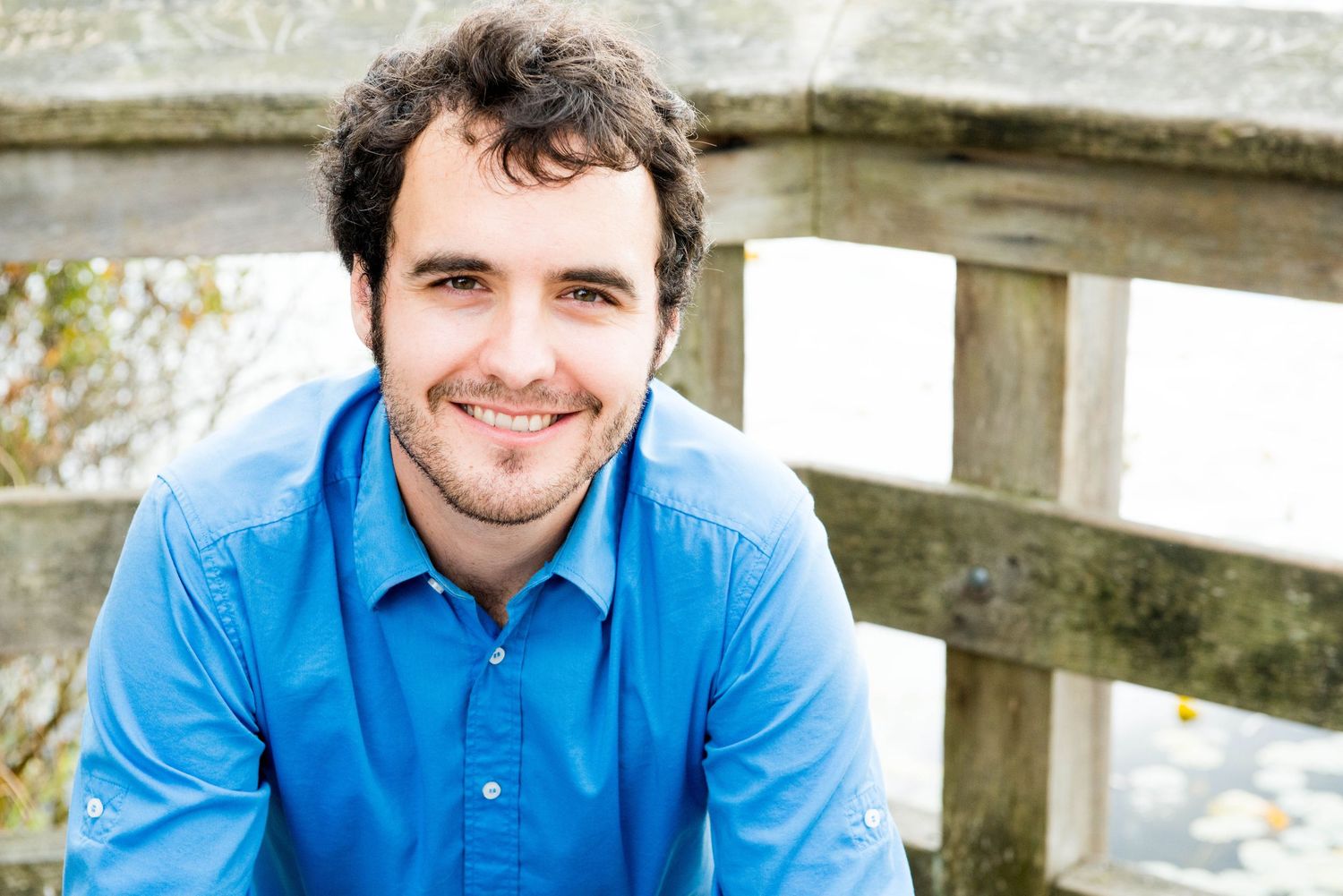 Outdoor portrait of a smiling man standing near a wooden fence in British Columbia.