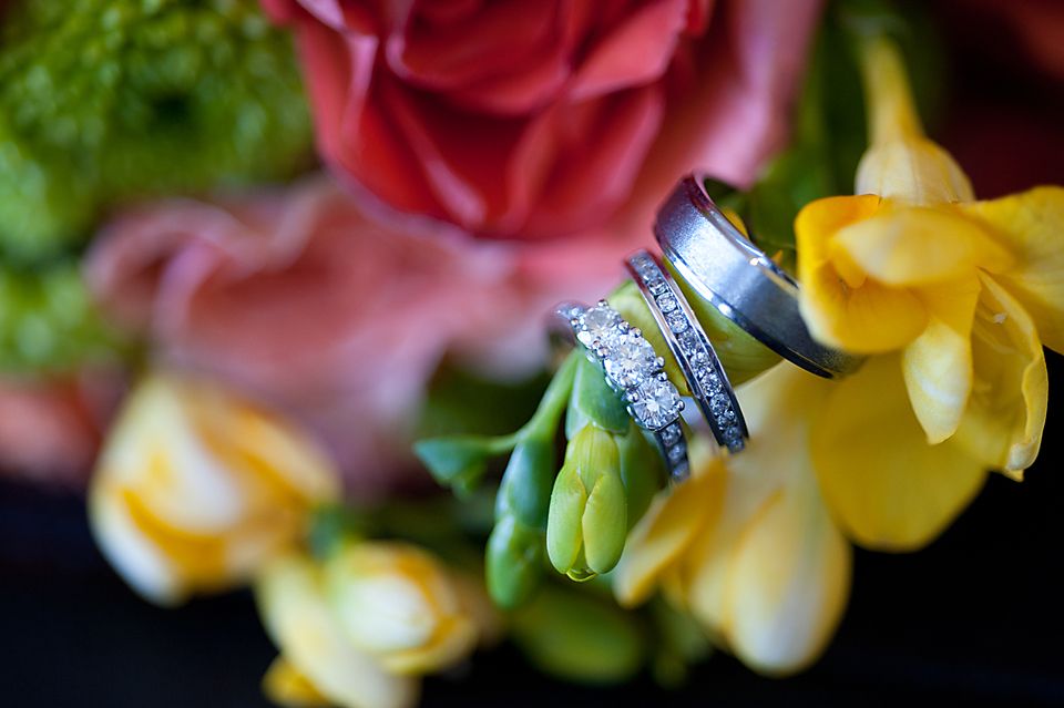 Wedding rings displayed on colourful flowers in a bridal bouquet.