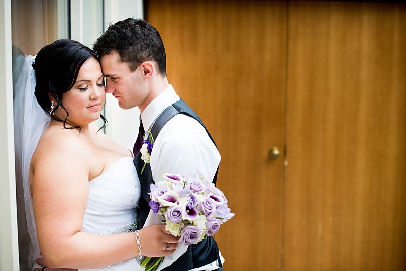 Bride and groom sharing a quiet moment during an indoor wedding portrait with a colourful bridal bouquet.