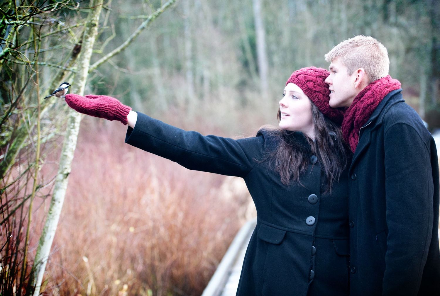Couple admiring a bird perched on the woman's hand during an outdoor engagement session.