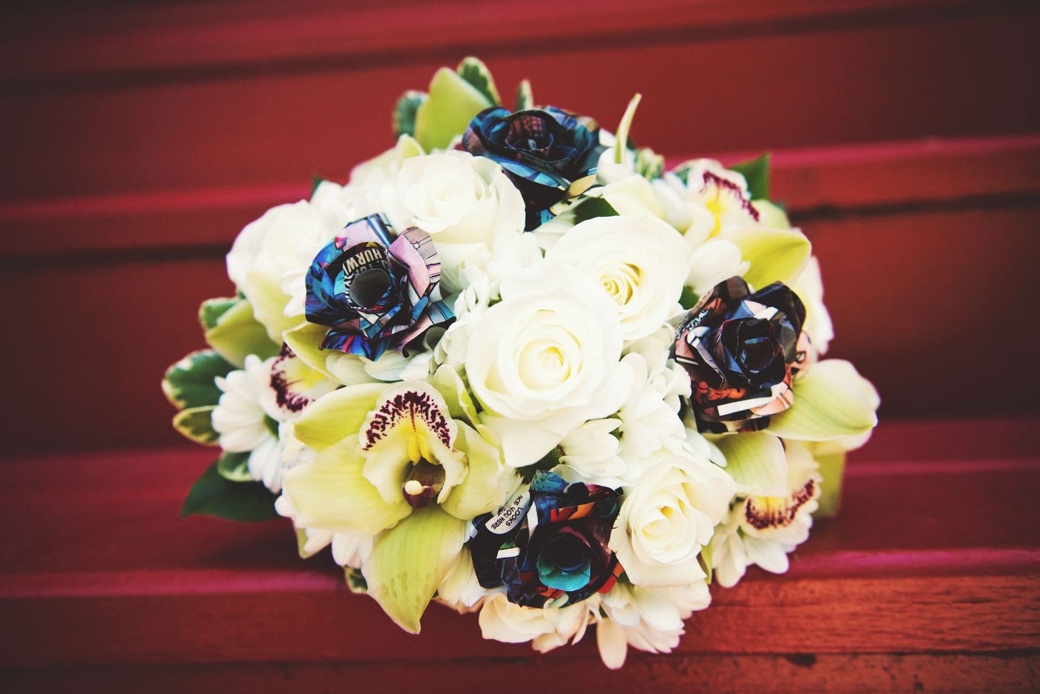 Bridal bouquet featuring white roses and handmade comic book flowers before a wedding ceremony.