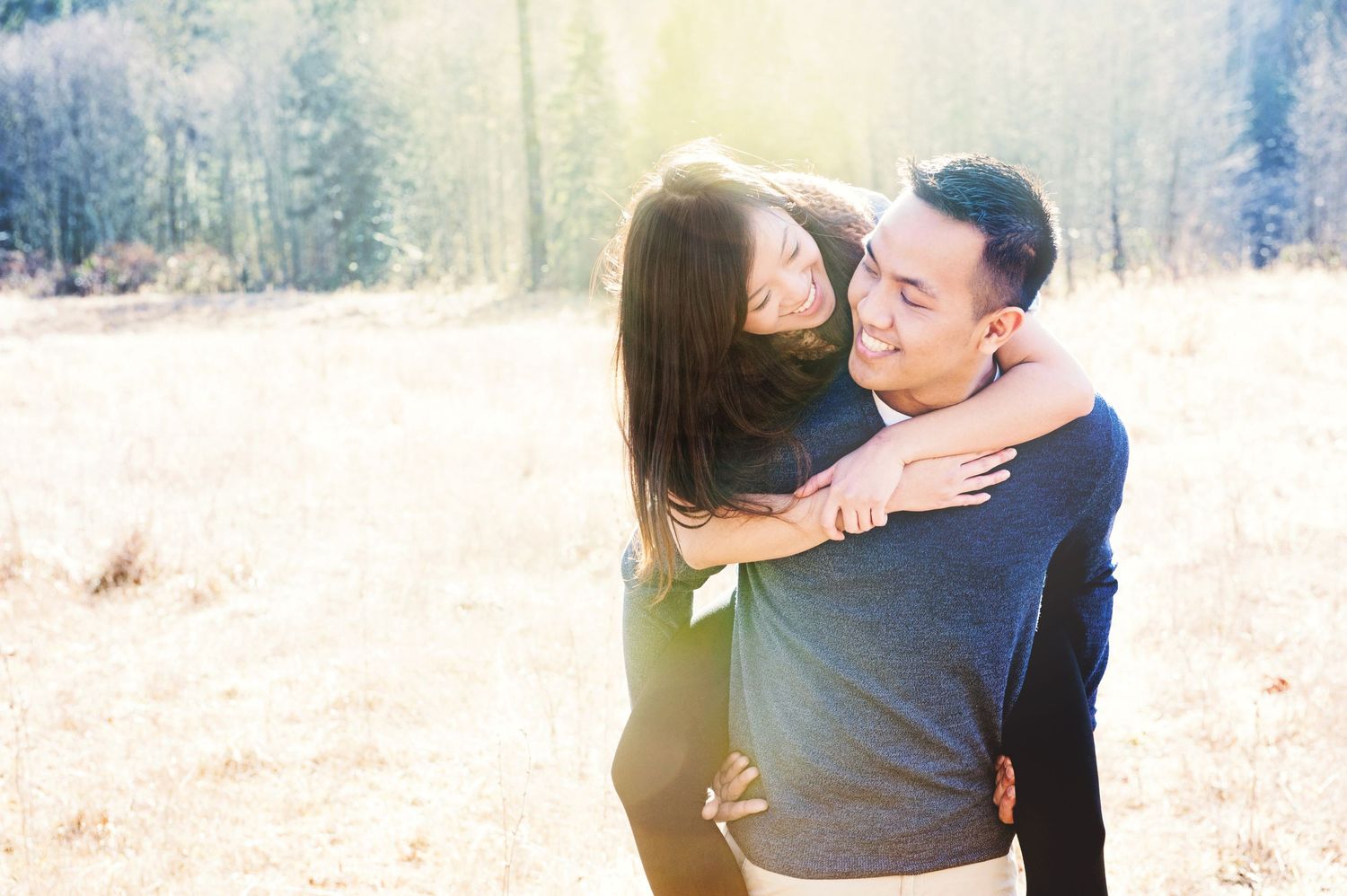 Couple embracing in a golden meadow during an engagement session in Chilliwack, British Columbia.