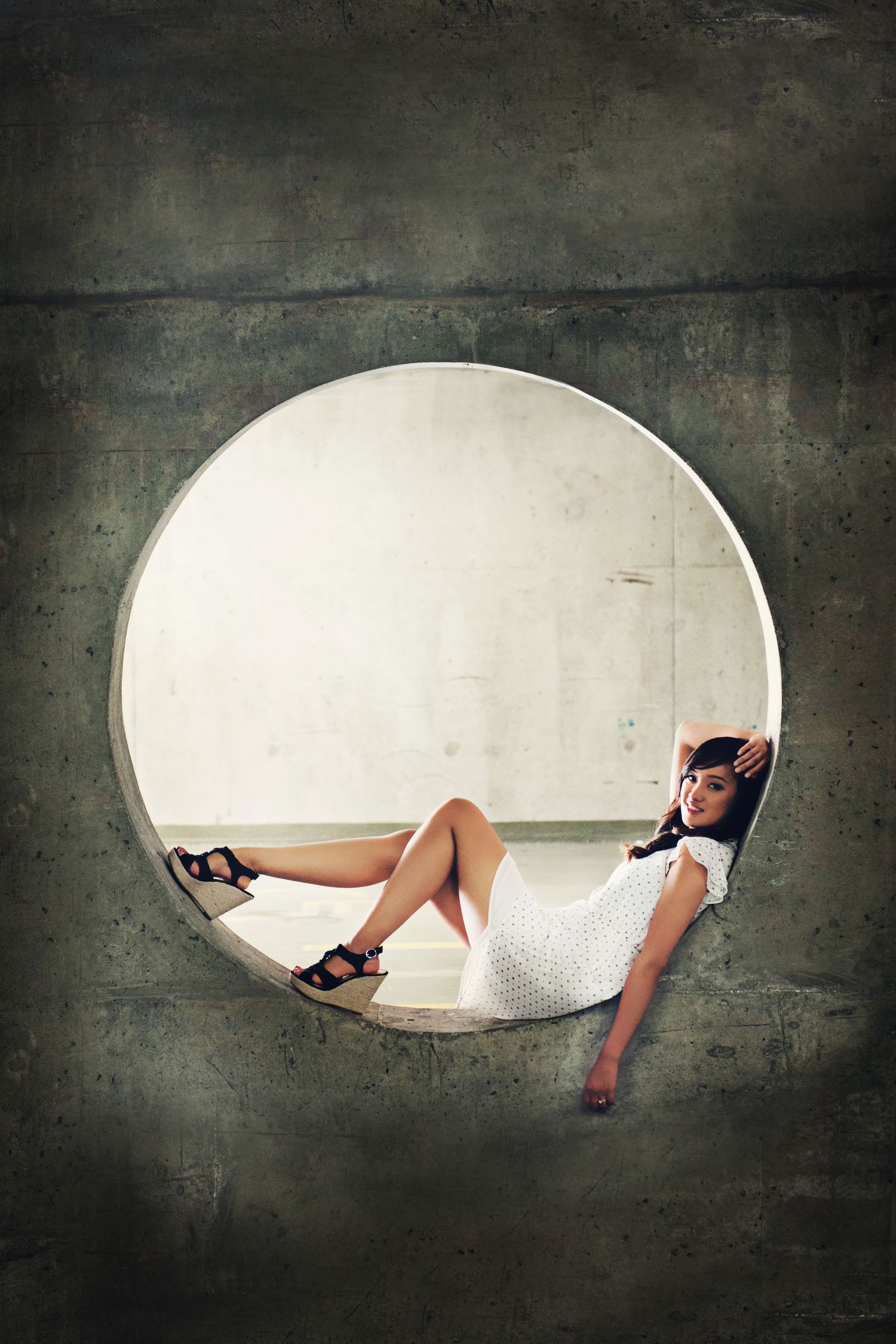 Portrait of a woman framed within a circular concrete structure in Vancouver, British Columbia.