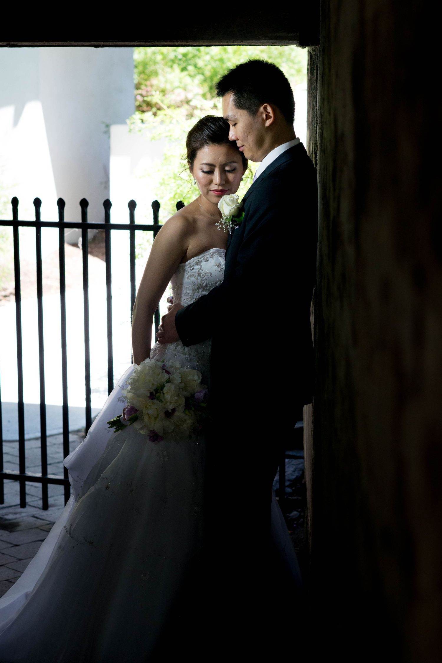 Bride and groom embracing in a shadowed archway during their wedding portraits in Toronto, Ontario.