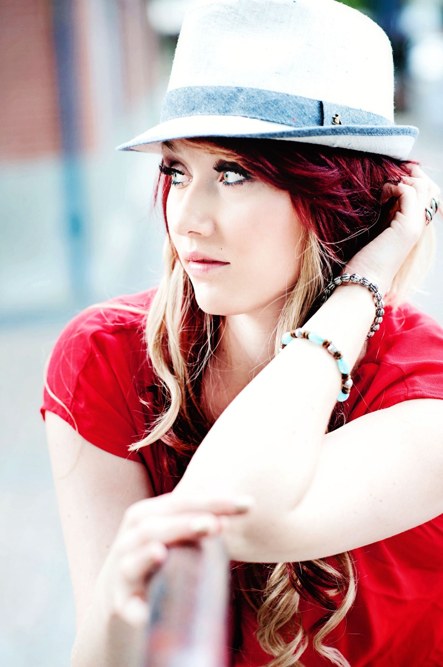 Young woman wearing a white fedora and red top during a relaxed outdoor portrait session in British Columbia.