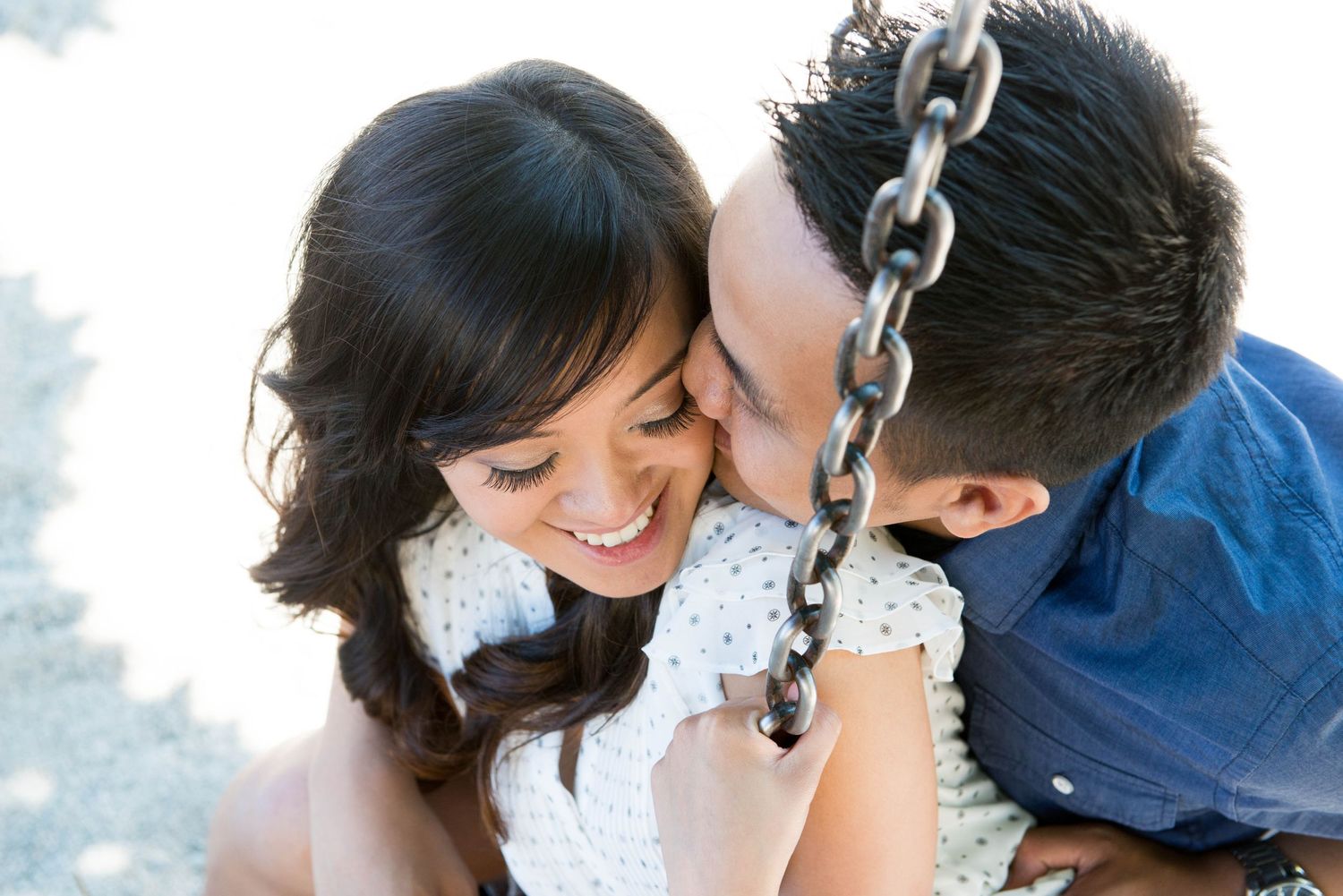Couple laughing together beside a swing during an outdoor engagement session.