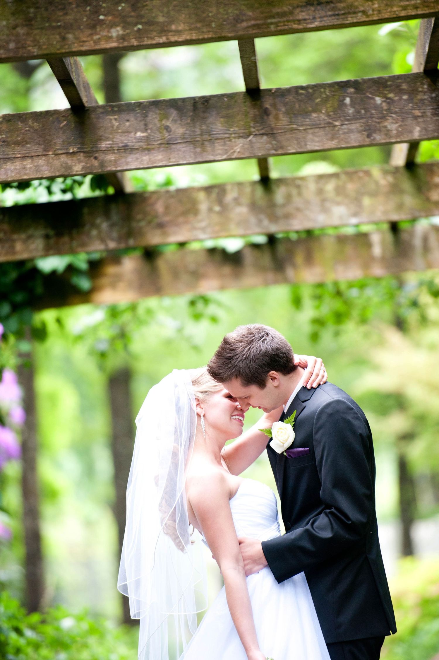 Bride and groom sharing a quiet moment beneath a wooden pergola at Minter Gardens in British Columbia.