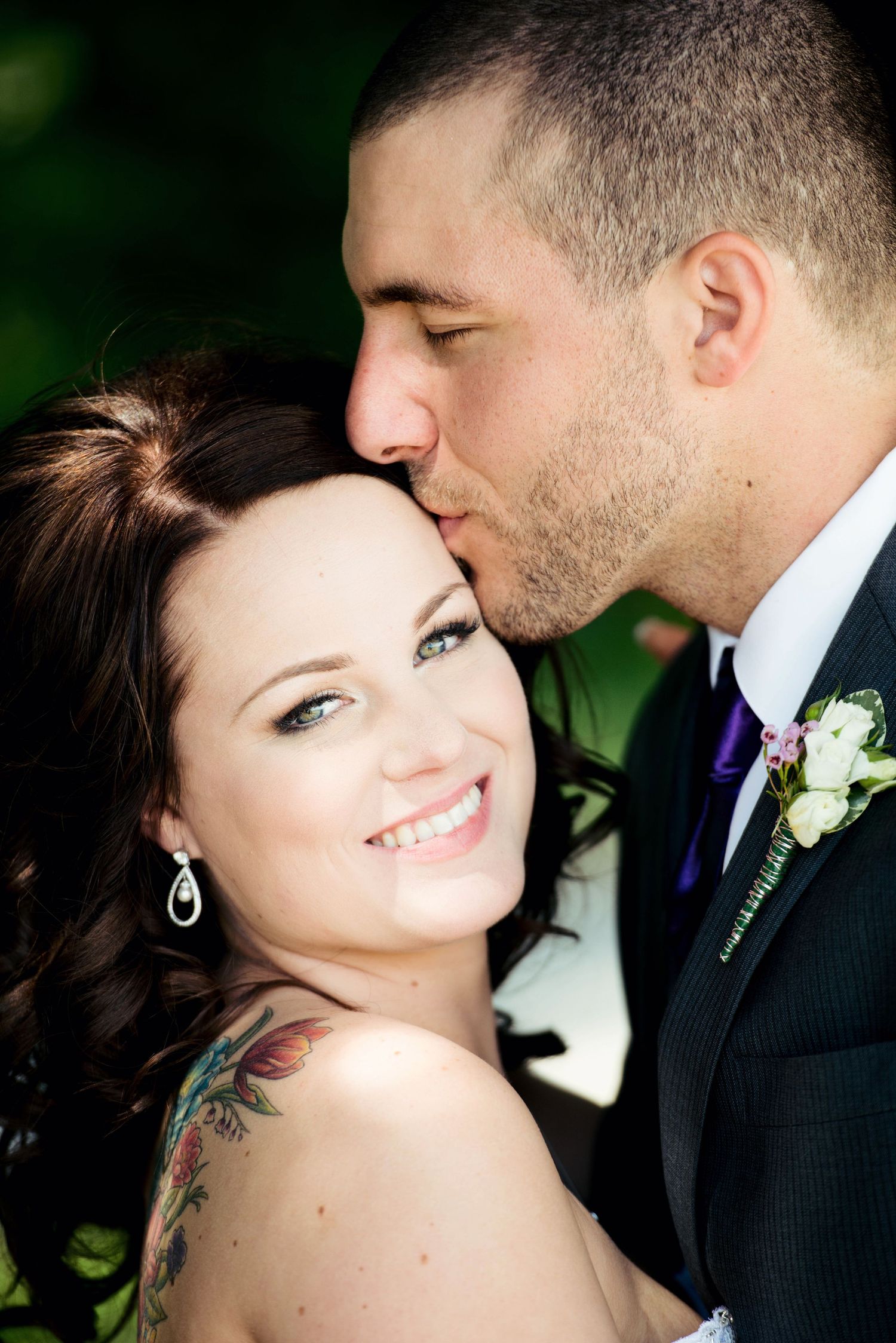 Groom kissing the bride's cheek during a joyful wedding portrait.